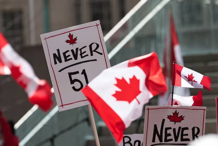 People holding Canadian flags and signs, including one reading "Never 51," possibly indicating a protest or demonstration