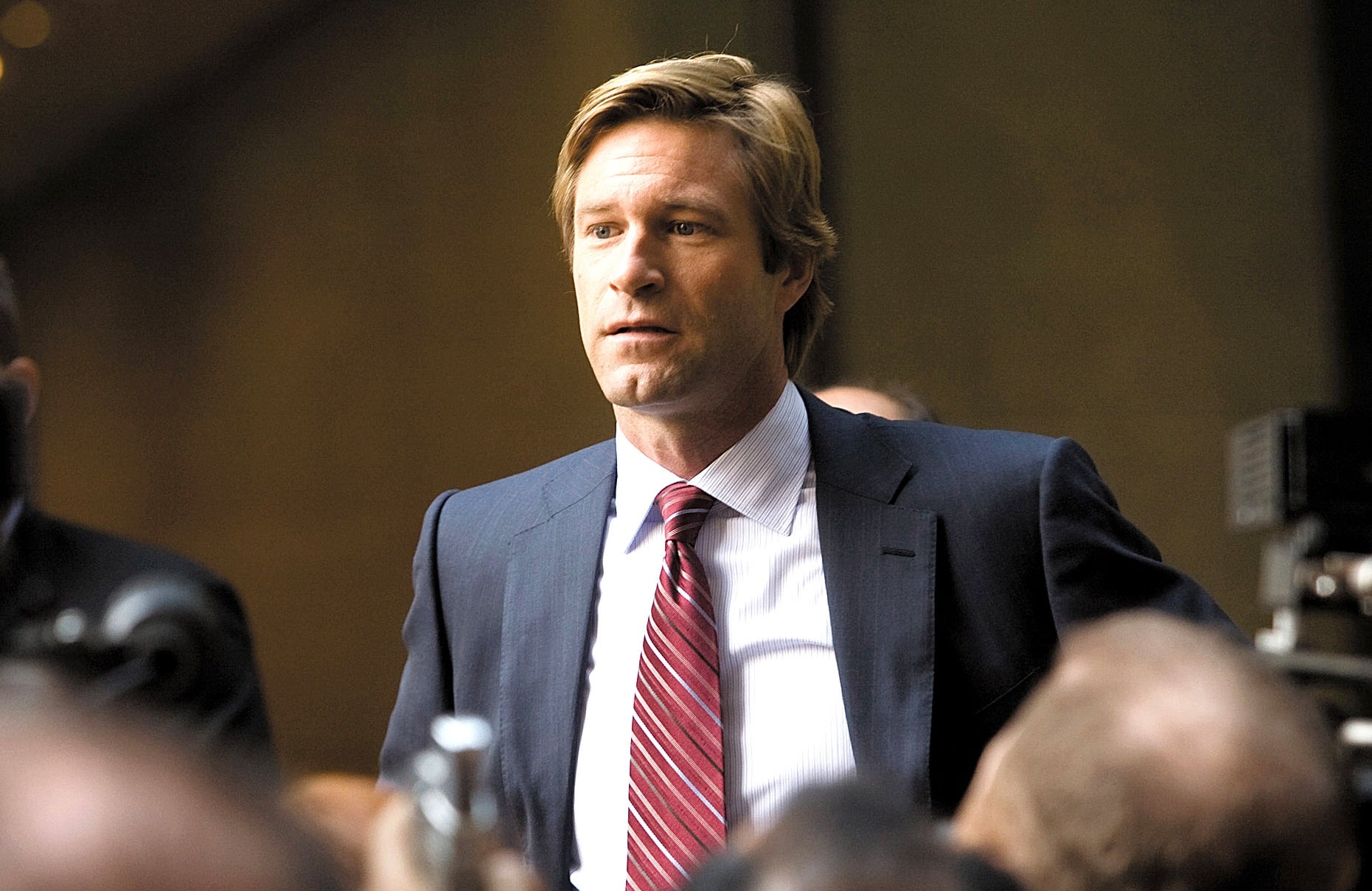 A person in a suit and tie is surrounded by media and cameras at an event