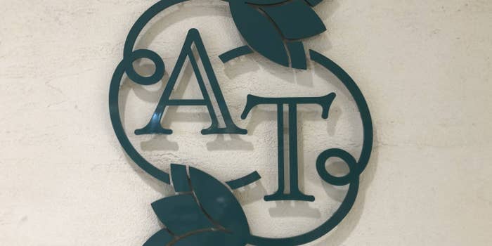 大きな文字「A」と「T」が重なり、葉のデザインが施されたロゴ。