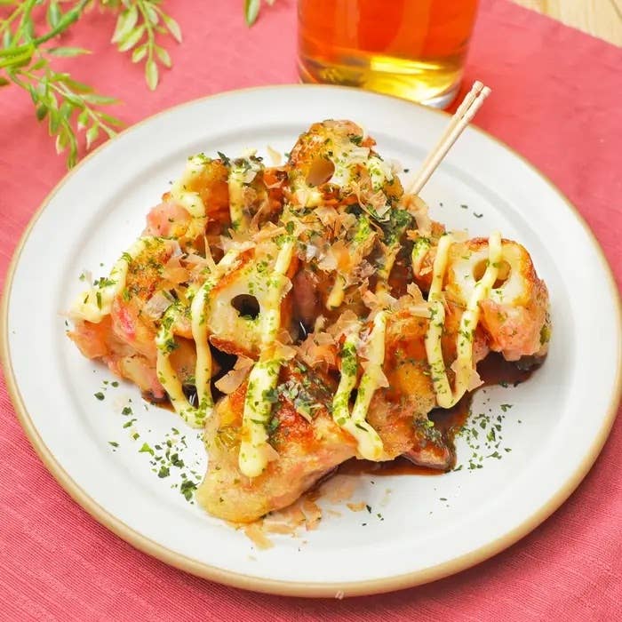 皿に盛られたタコ焼きがテーブルに置かれている。タコ焼きにマヨネーズと青のりがかかっている。