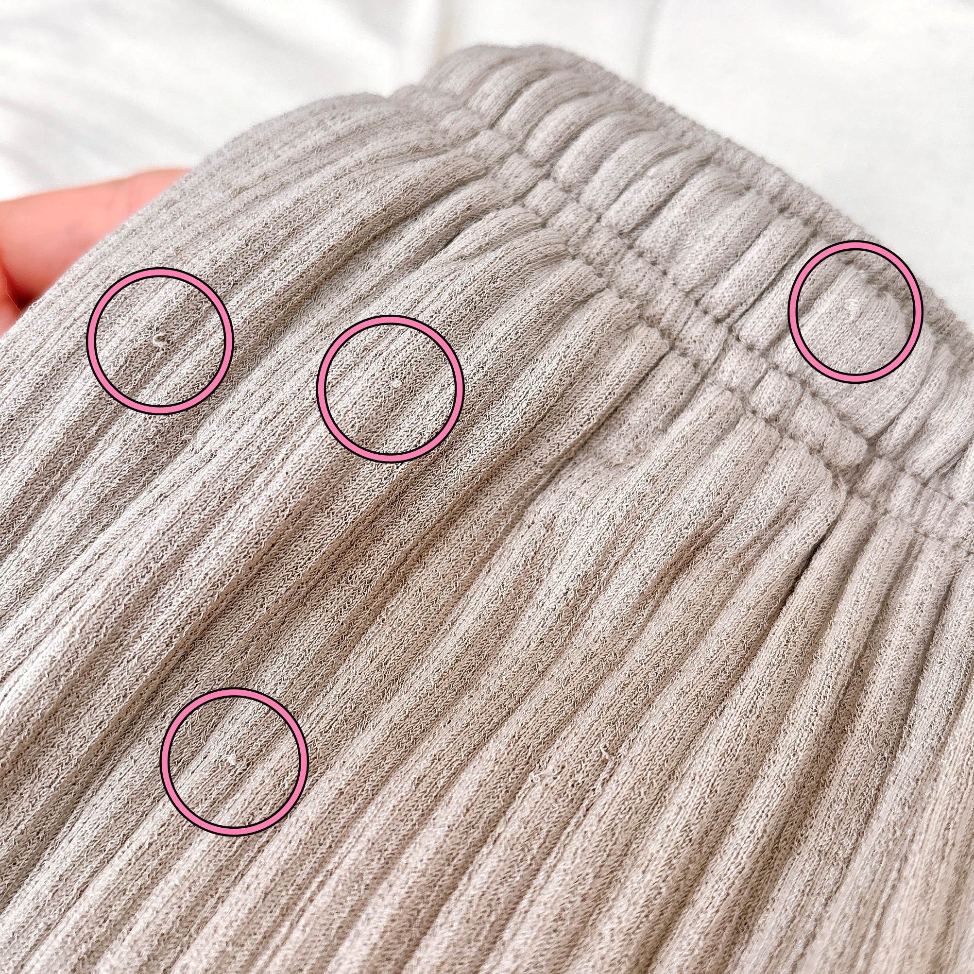 布に小さな穴が開いているズーム画像。複数の赤い円で強調表示。