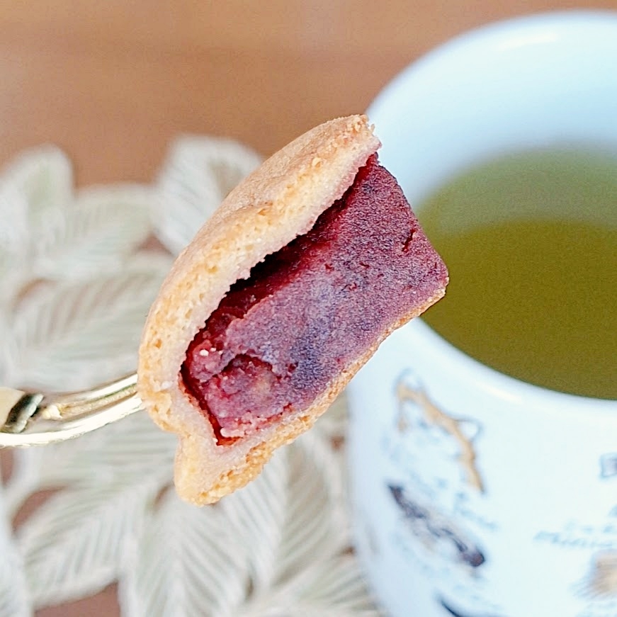 あんこを挟んだ和菓子がフォークに刺され、近くに緑茶の入ったマグカップが置かれている。