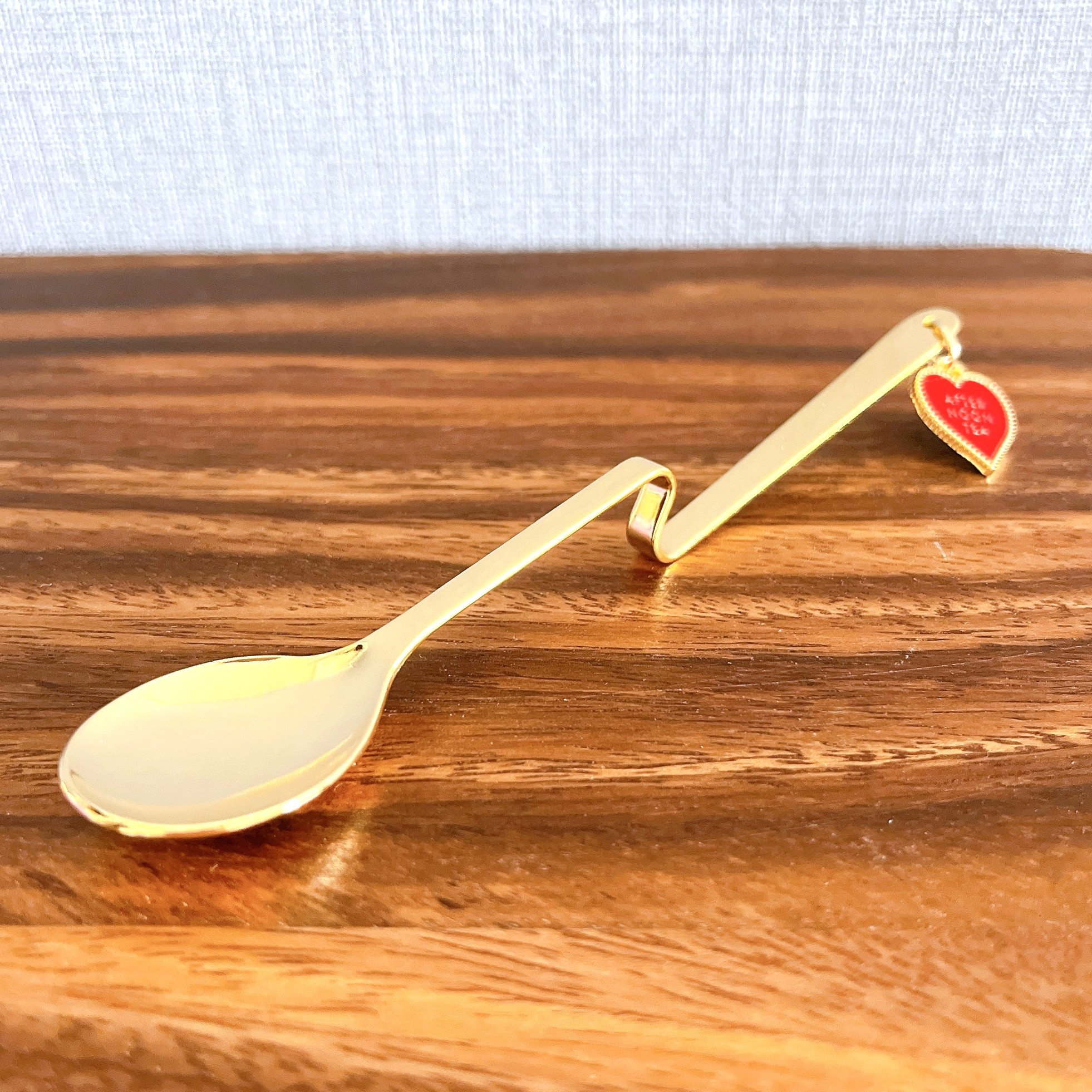 金色のスプーンが木製のテーブルの上に置かれており、ハートの装飾が付いている。