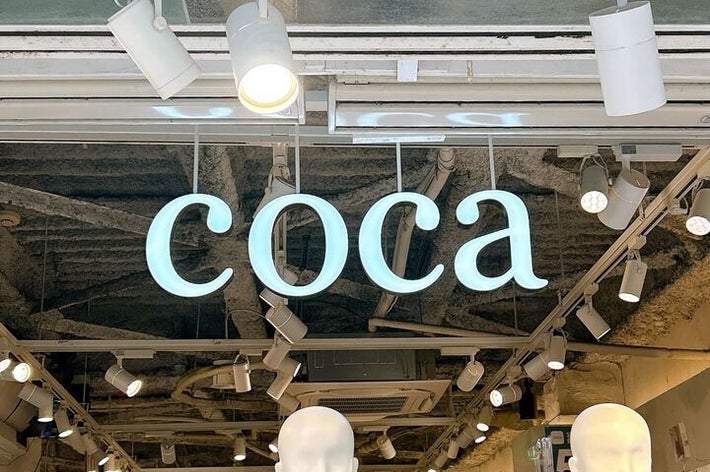 店の入り口に「coca」の看板が掲げられ、室内は照明に照らされている。