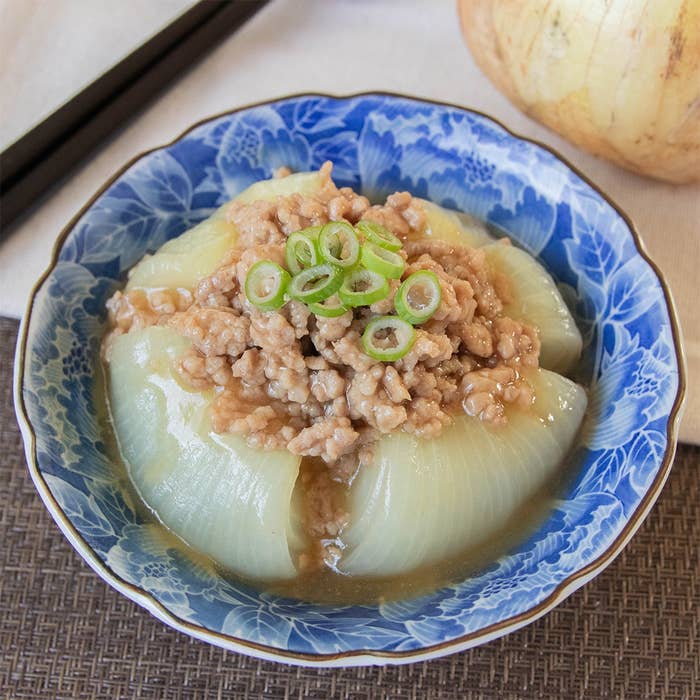 器に盛られたタマネギとひき肉の料理。青い模様の器に盛られ、上には刻んだネギが添えられている。