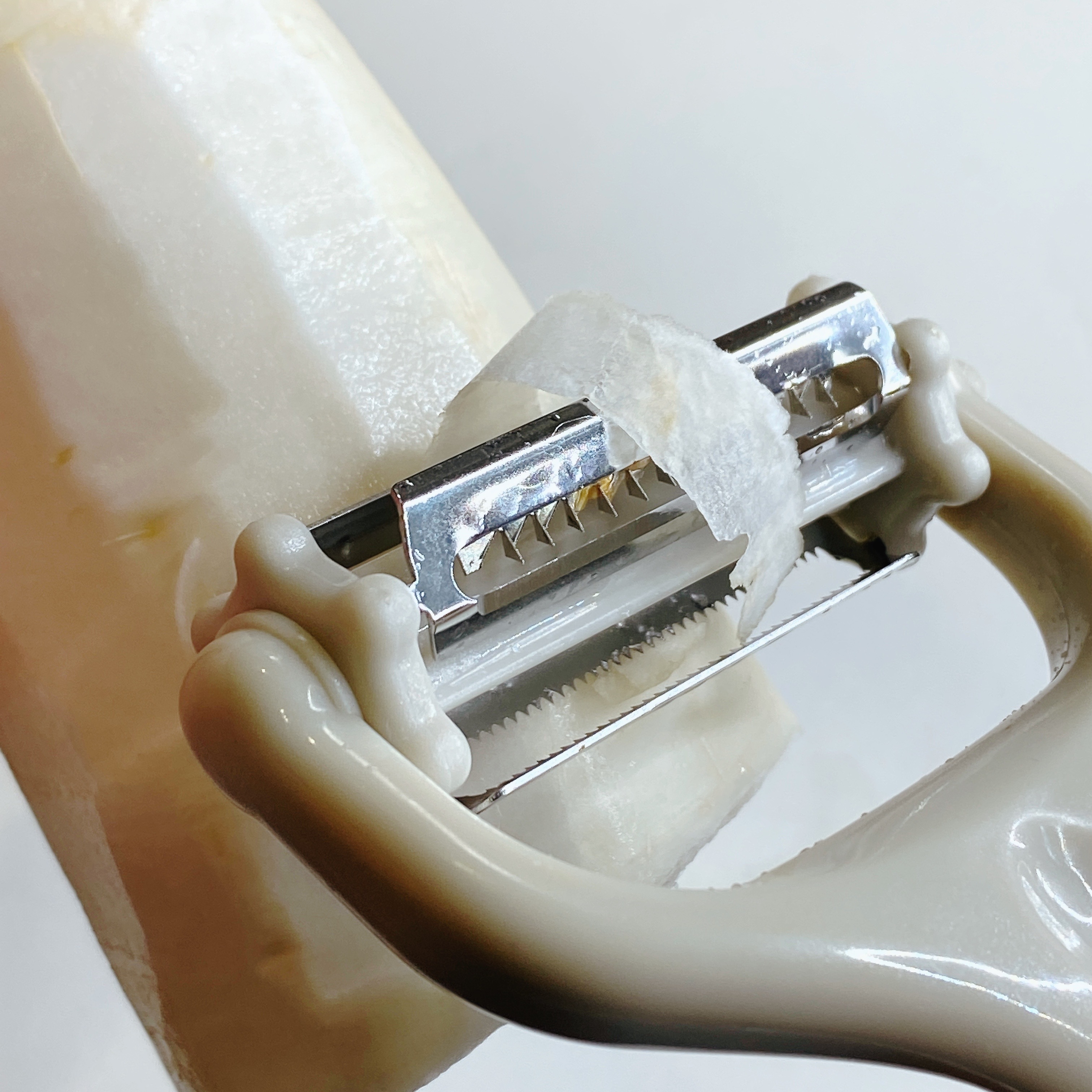 ピーラーで大根の皮を剥いている様子。