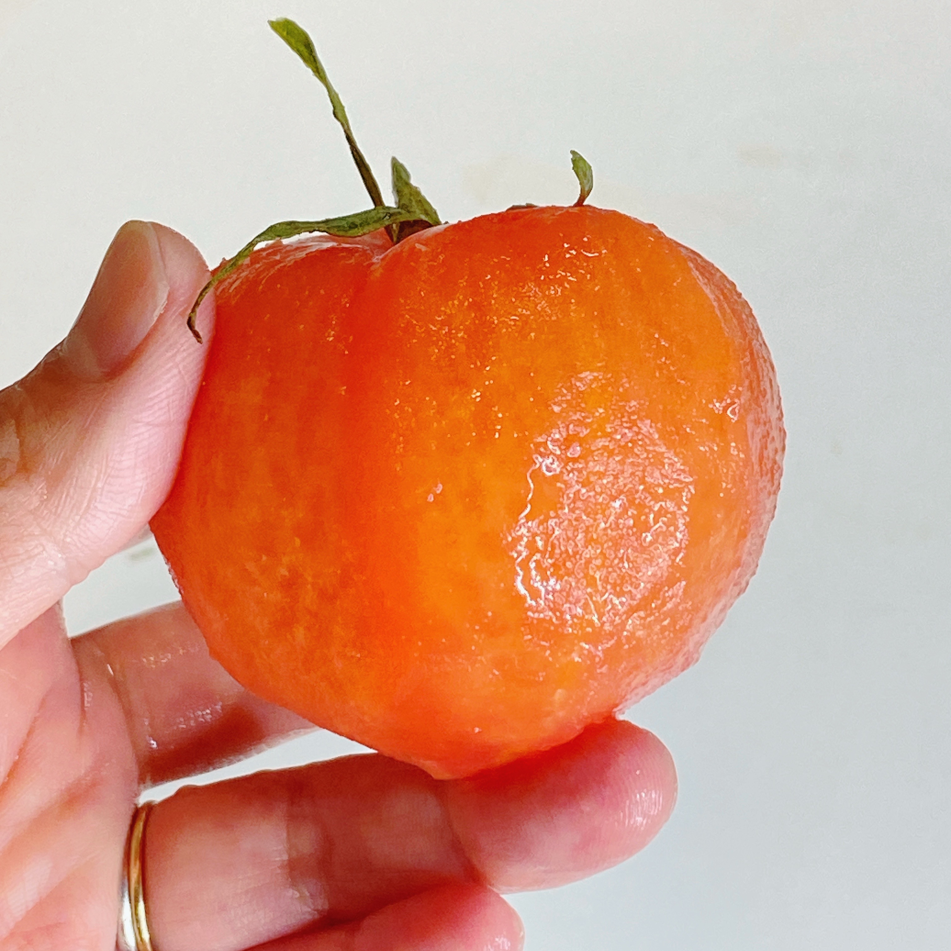 手で持った皮を剥いたトマト。