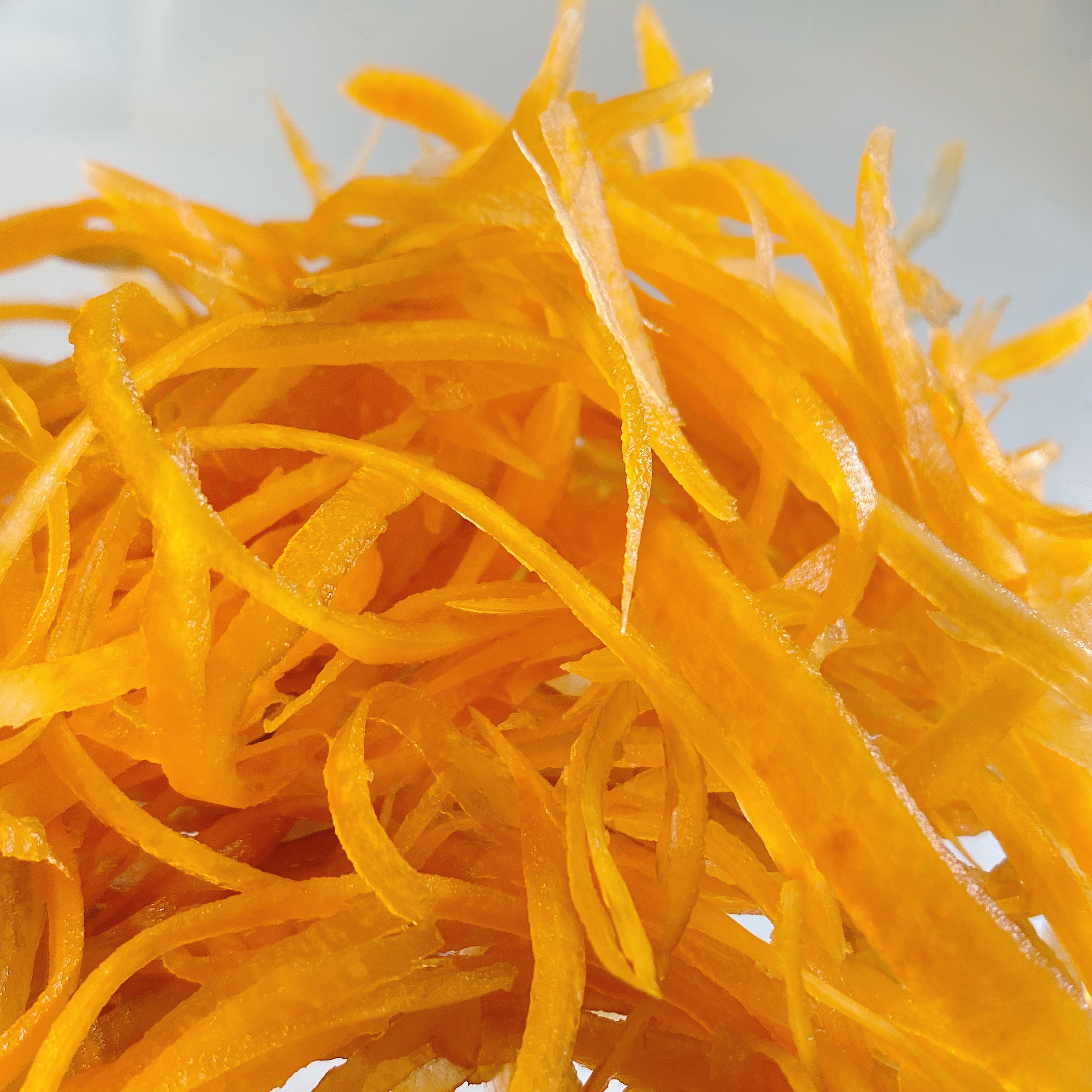 細切りのオレンジ色の野菜が重なっている。繊細な形状が際立っている。