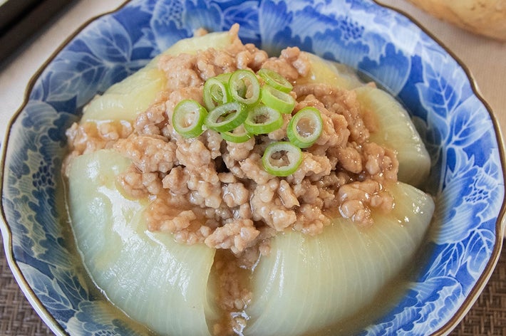 玉ねぎを丸ごと使ったひき肉あんかけ料理。青い器に盛られ、ネギがトッピングされています。