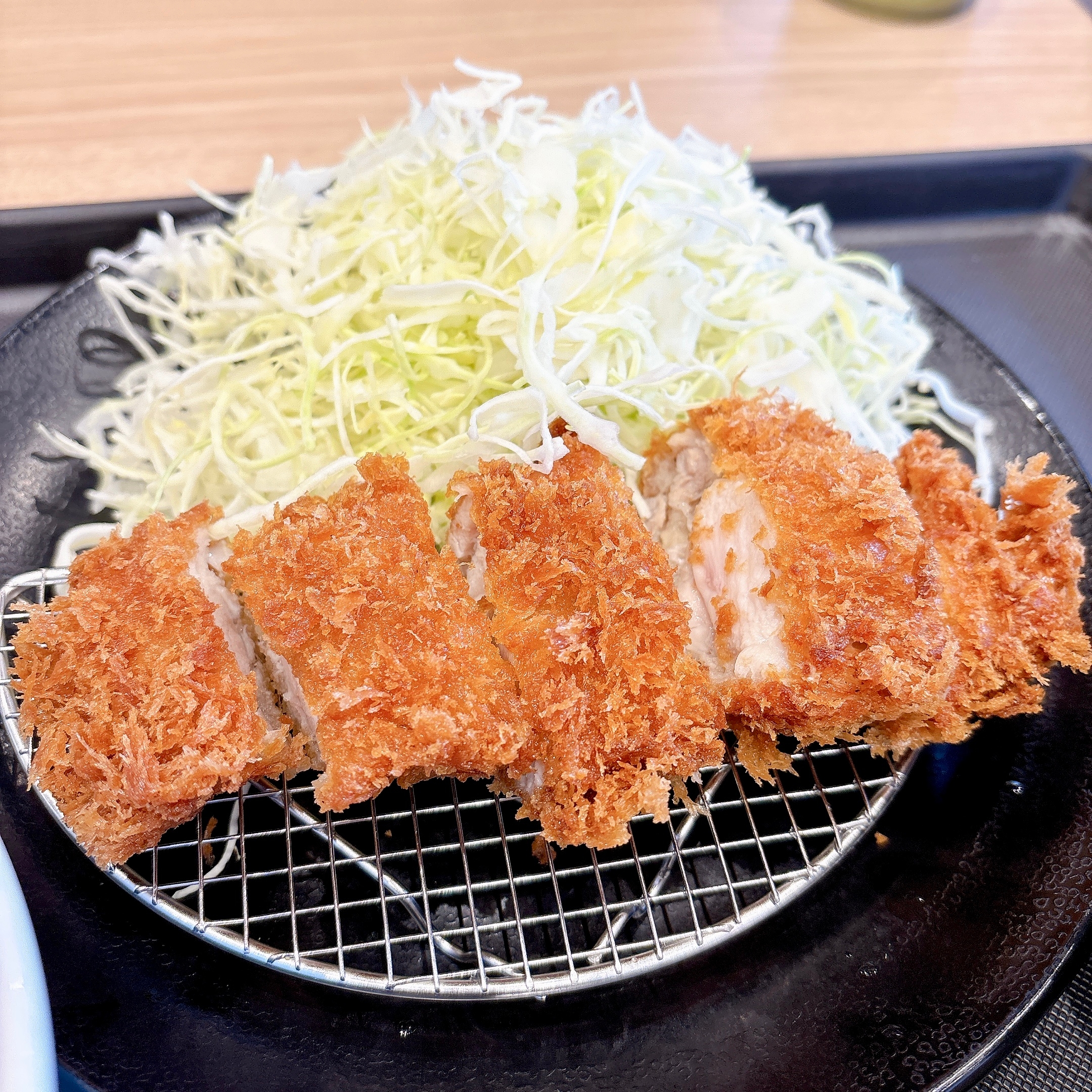 とんかつと千切りキャベツの料理が黒い皿に盛られている。