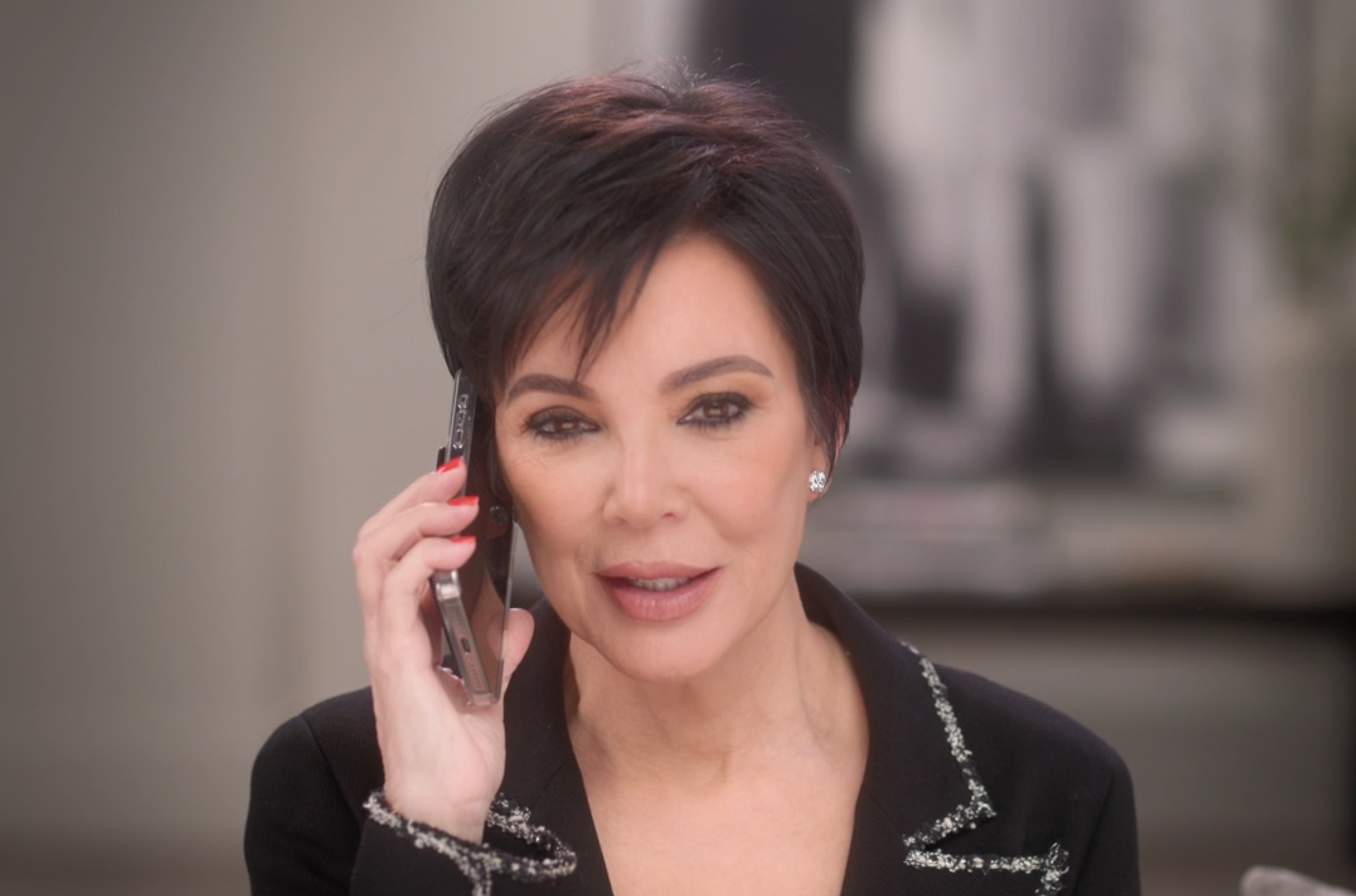 Kris Jenner talking on a phone while sitting on a sofa