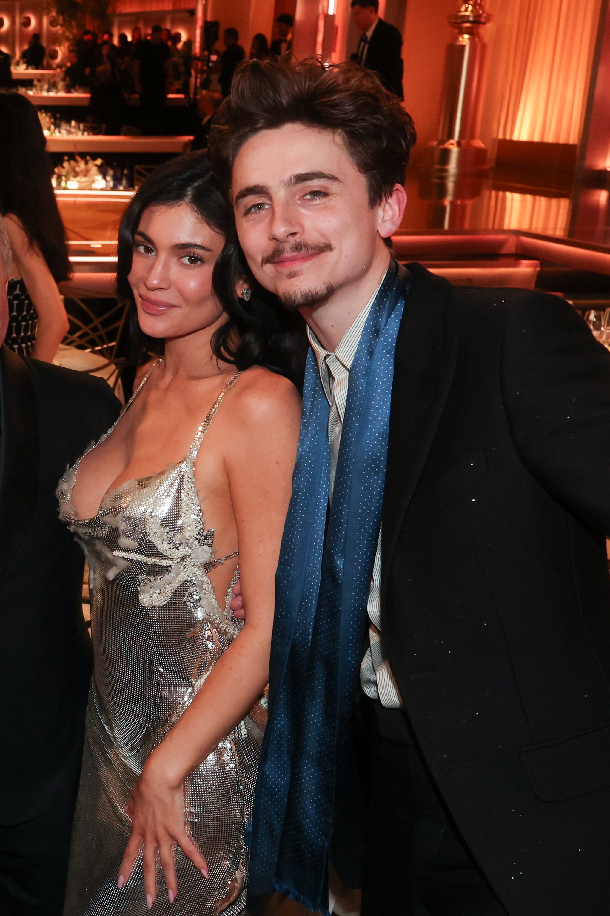 Kylie Jenner in a low-cut, shimmering dress, posing next to Timothée Chalamet at an event