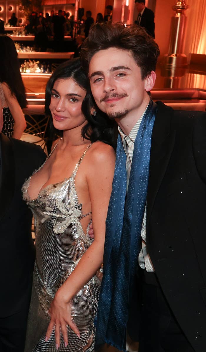 Kylie Jenner in a low-cut, shimmering dress, posing next to Timothée Chalamet at an event