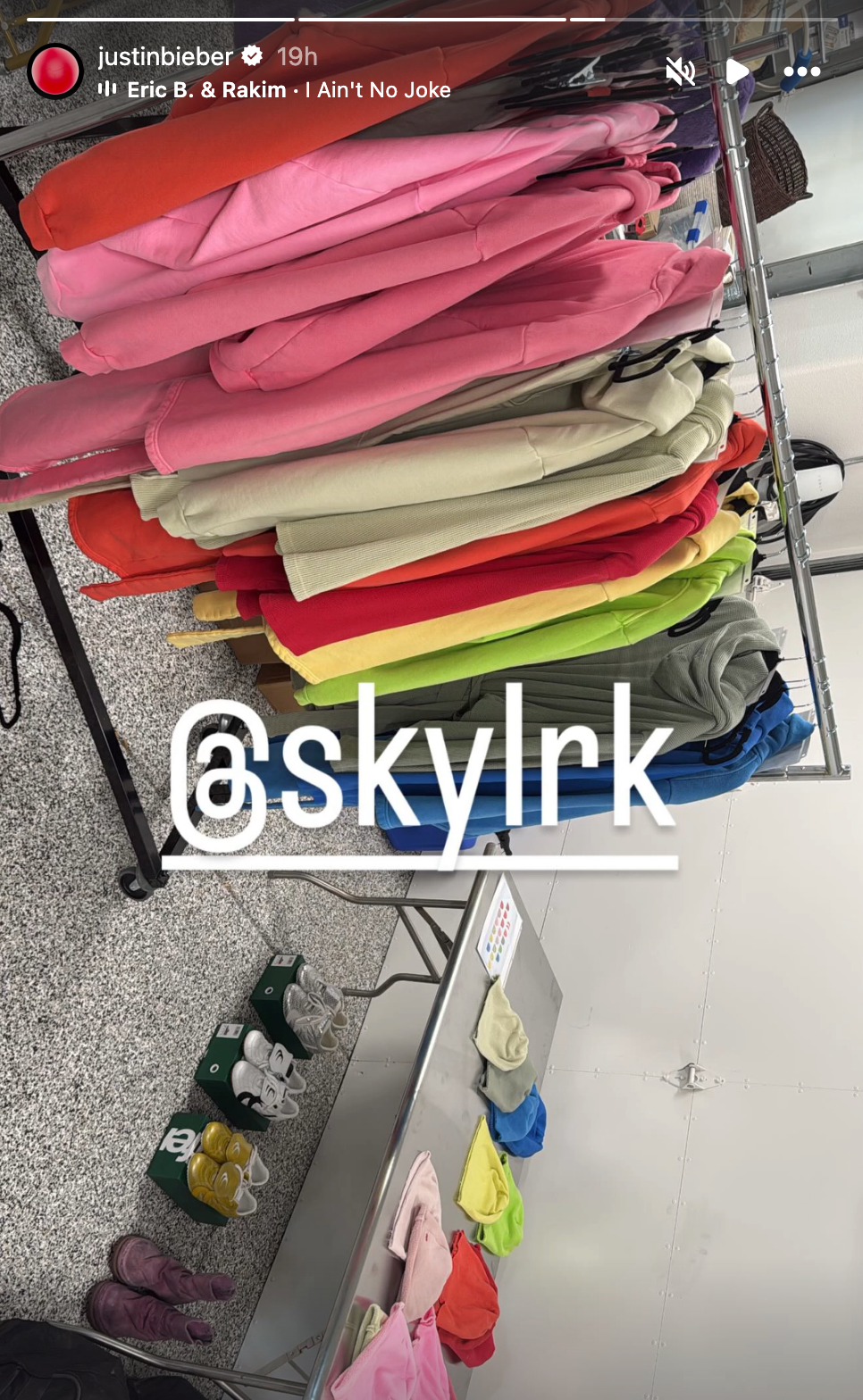 Clothing rack with colorful hoodies and jackets, some shoes beneath. Username "@skylrk" overlayed. Song playing: "I Ain't No Joke" by Eric B. & Rakim