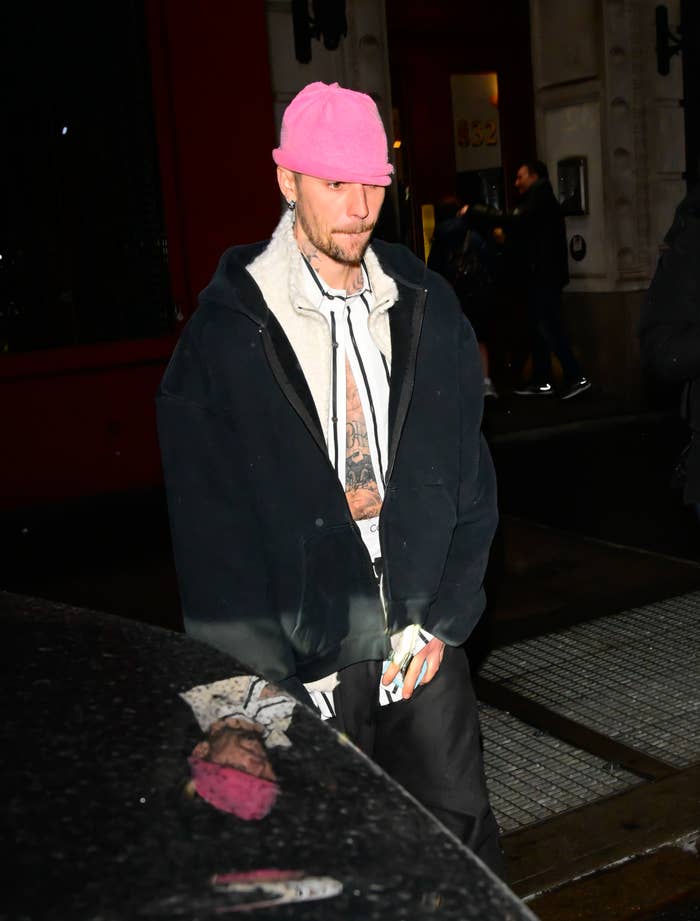 A person wearing casual, oversized streetwear with a pink beanie is walking outside
