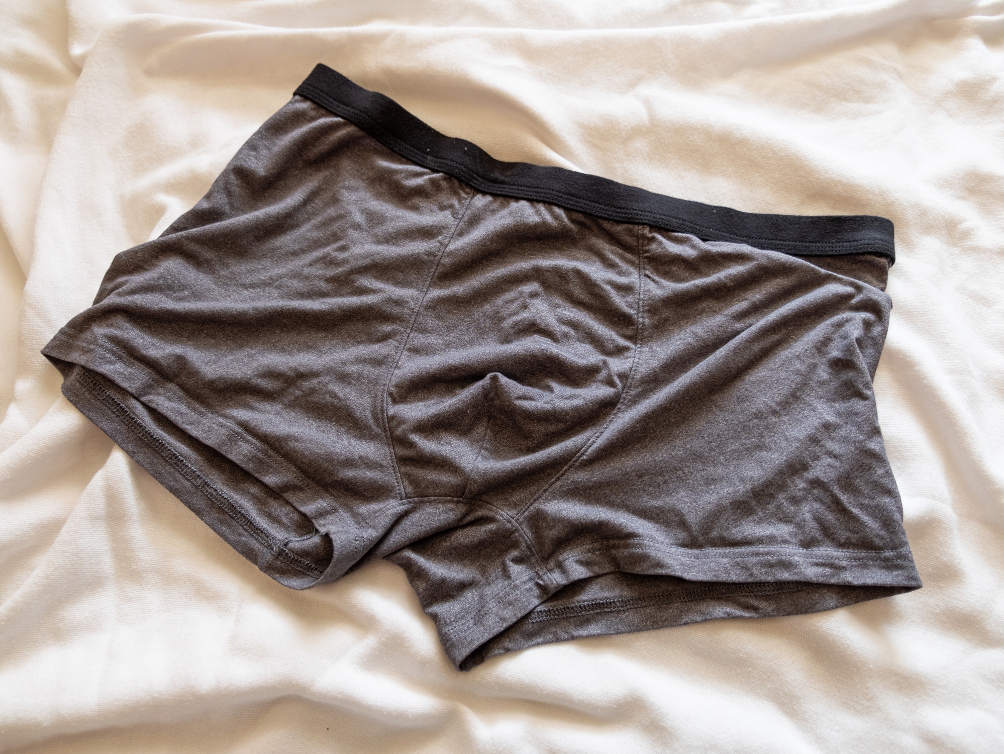 A pair of men's boxer briefs on a bed, suggesting themes of intimacy and everyday fashion