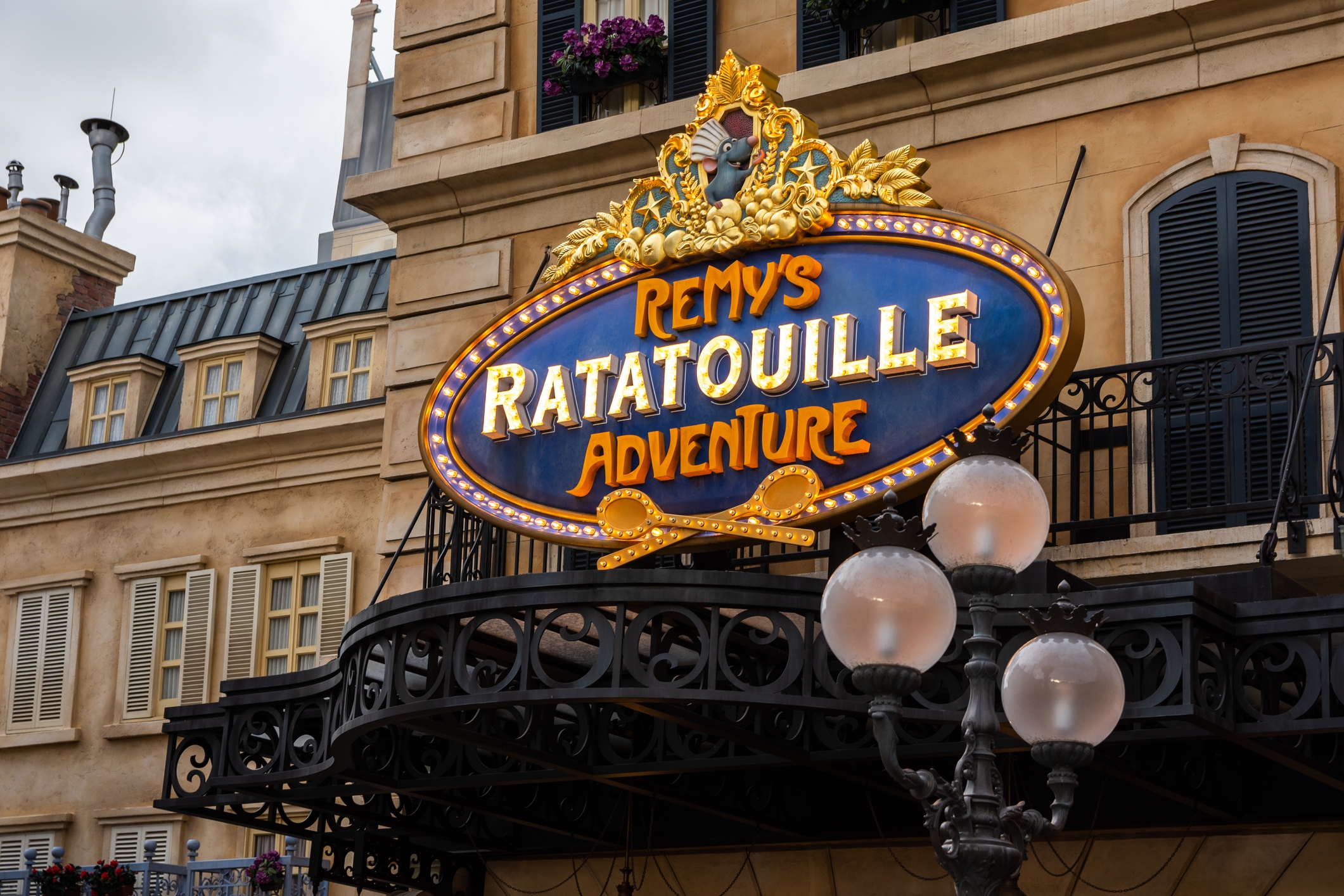 Sign for "Remy's Ratatouille Adventure" on a Parisian-style building facade, indicating an adventure attraction