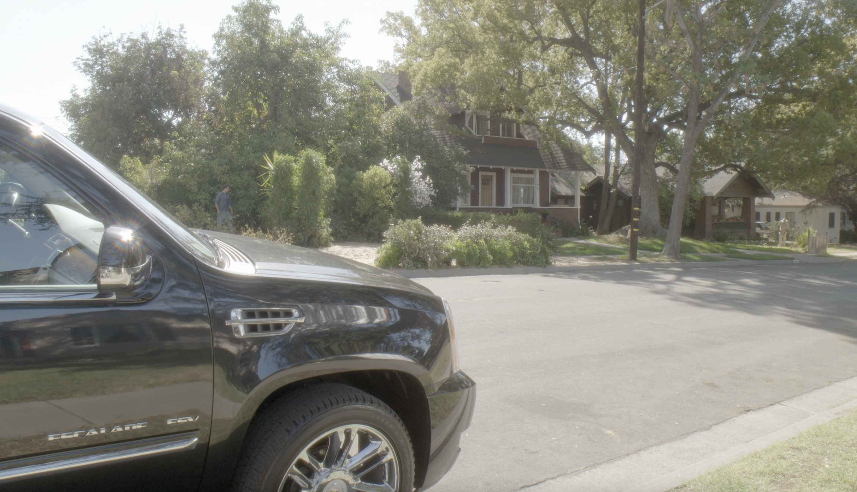 Parked luxury SUV on a residential street with houses and trees in the background