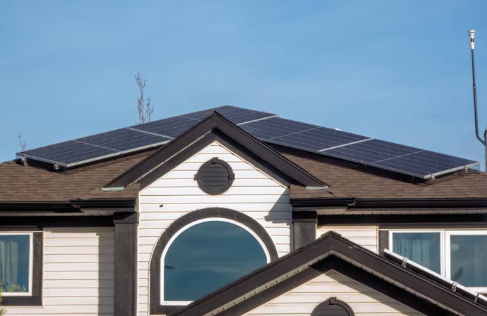 House with solar panels installed on the roof against a clear sky