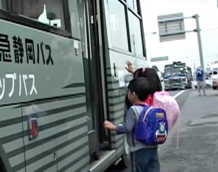 Young children with backpacks boarding a bus
