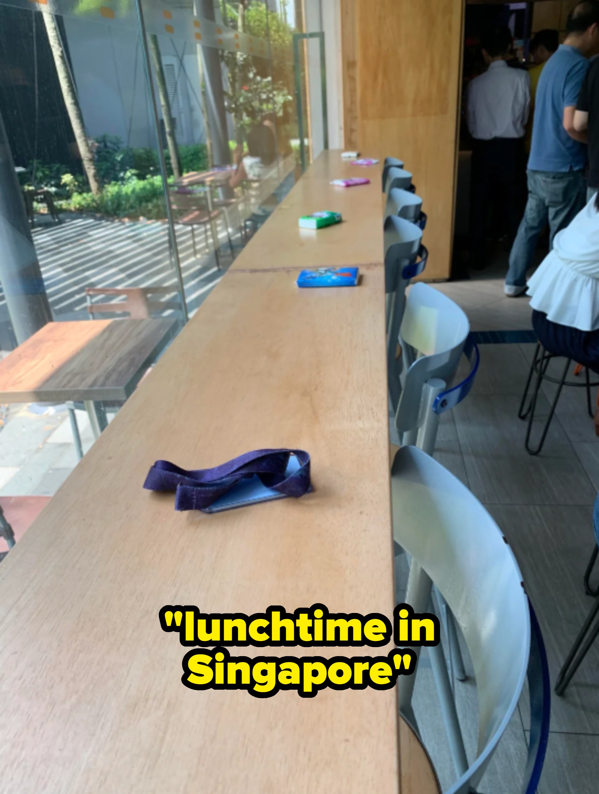 Wooden counter with empty seats, lanyards and small items spaced along the counter, suggesting a reserved or organized seating area