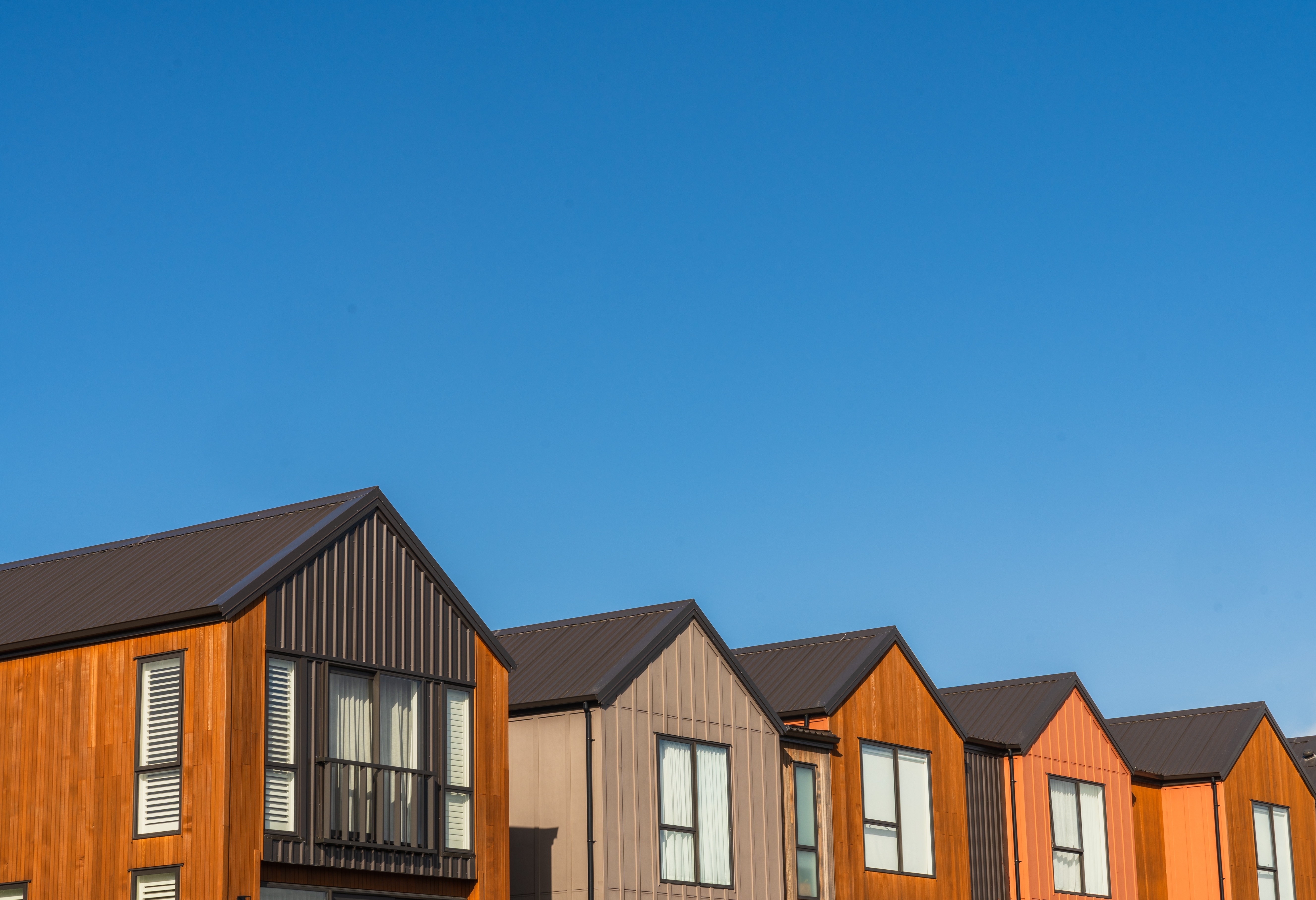 Row of modern houses with pitched roofs under a clear sky