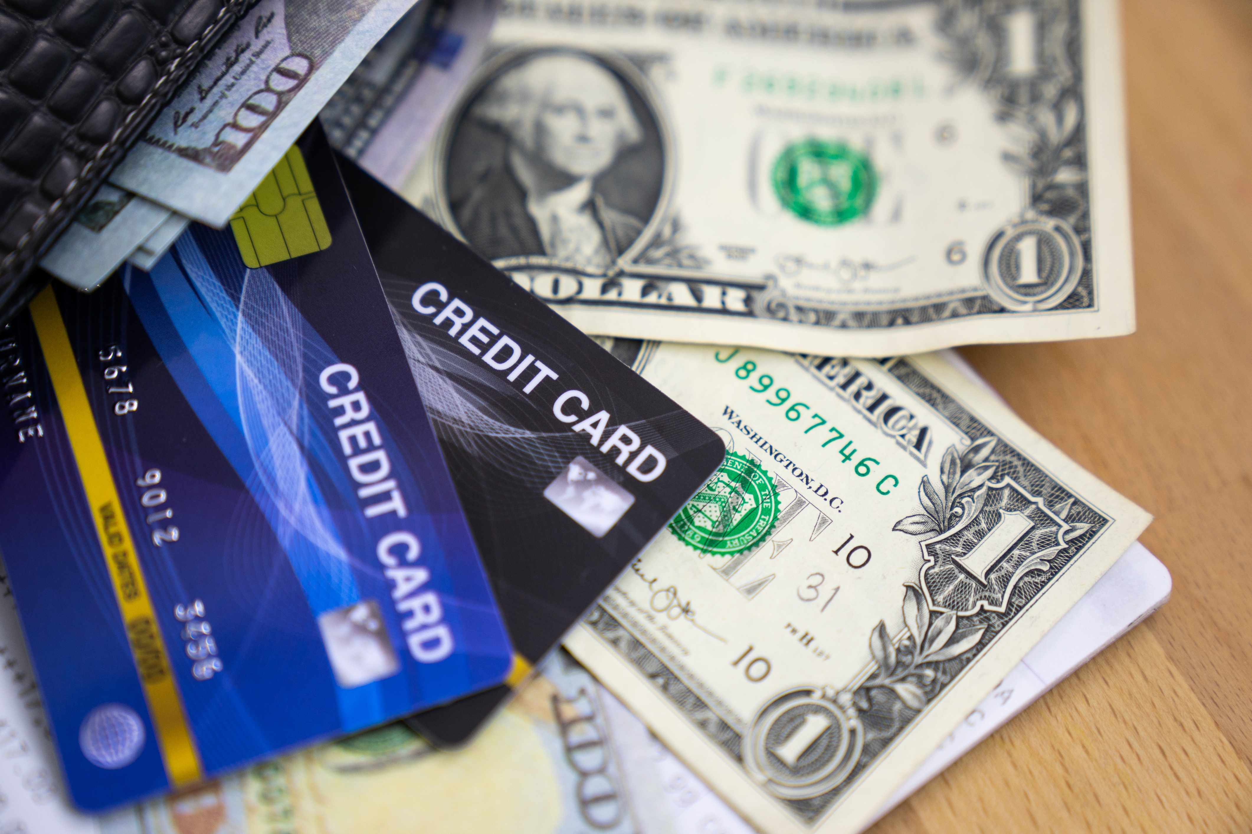 Credit cards and dollar bills are scattered on a table, suggesting personal finance or shopping