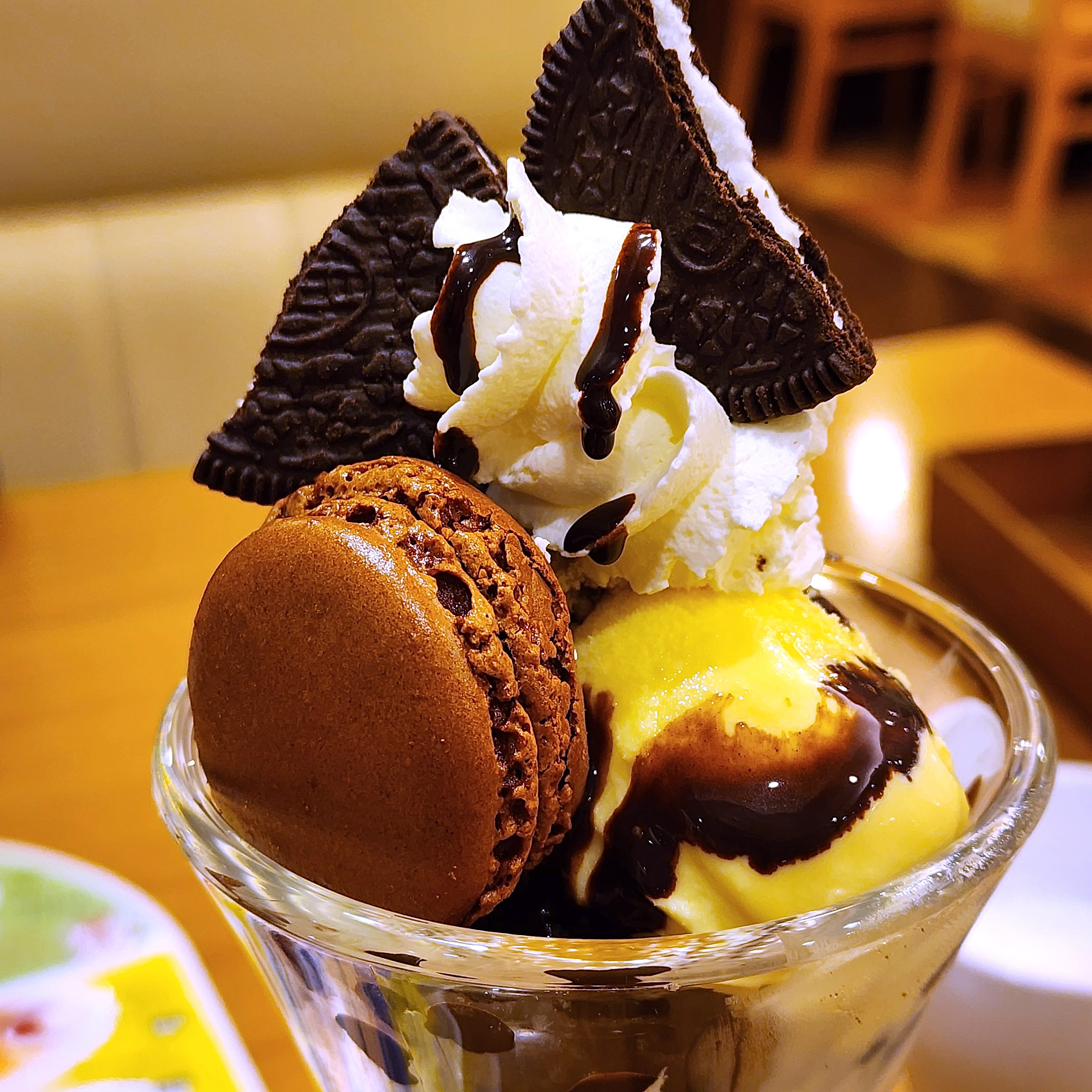デザートパフェにアイスクリーム、マカロン、ビスケット、ホイップクリームが載ったおいしそうな盛り付け。