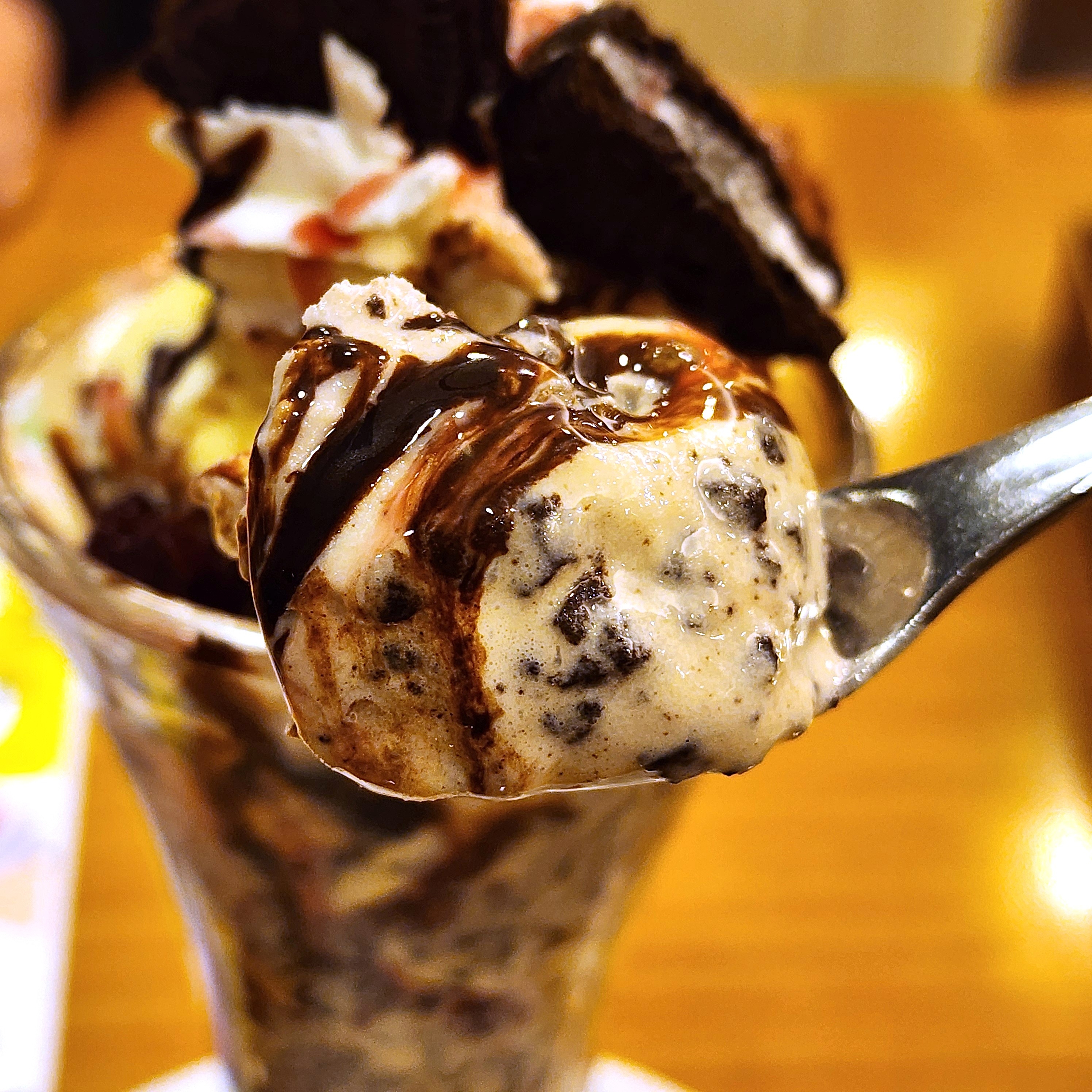 アイスクリームパフェのクローズアップ。スプーンにはクッキーが入ったアイスクリームがすくわれている。
