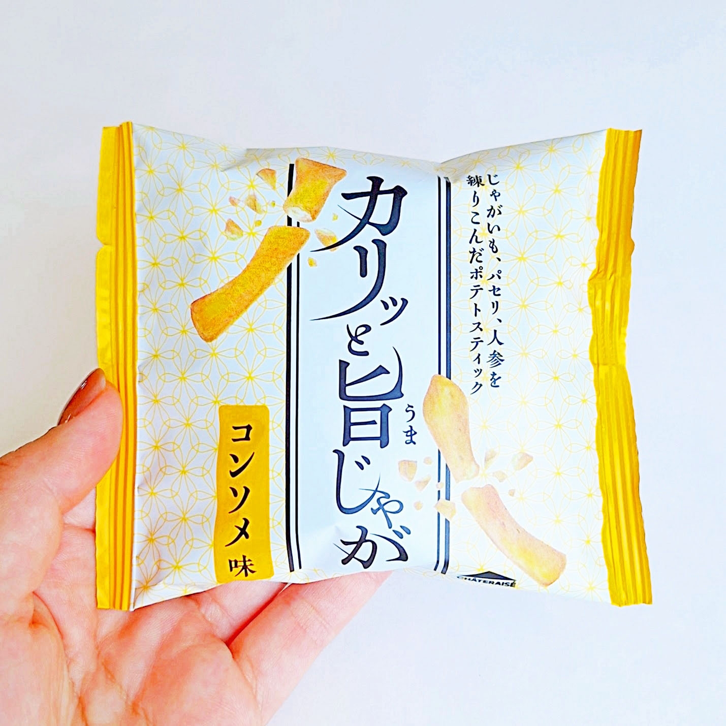 手に持たれた「カリッと旨じゃが」コンソメ味というポテトスティックのパッケージ。