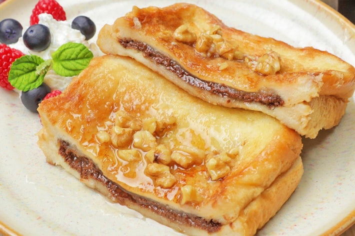 フレンチトーストにナッツとシロップがかかった朝食、フルーツとクリーム添え。