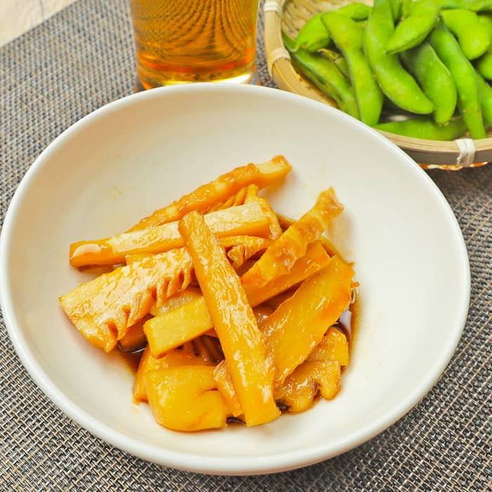 タケノコの煮物と枝豆が小皿に盛られており、奥に飲み物が置かれた食卓の一部。