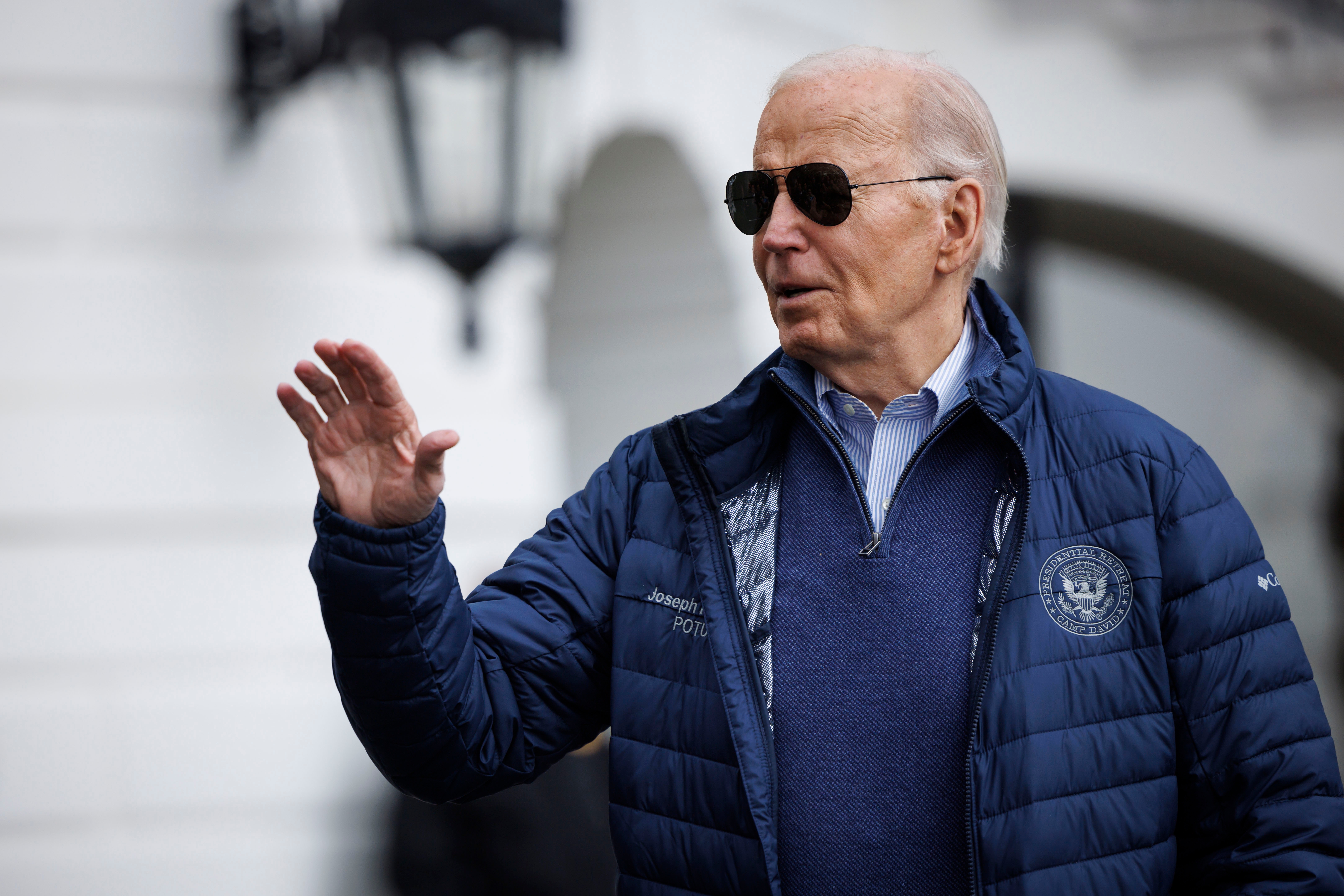 President Joe Biden in sunglasses and a jacket, waving outdoors