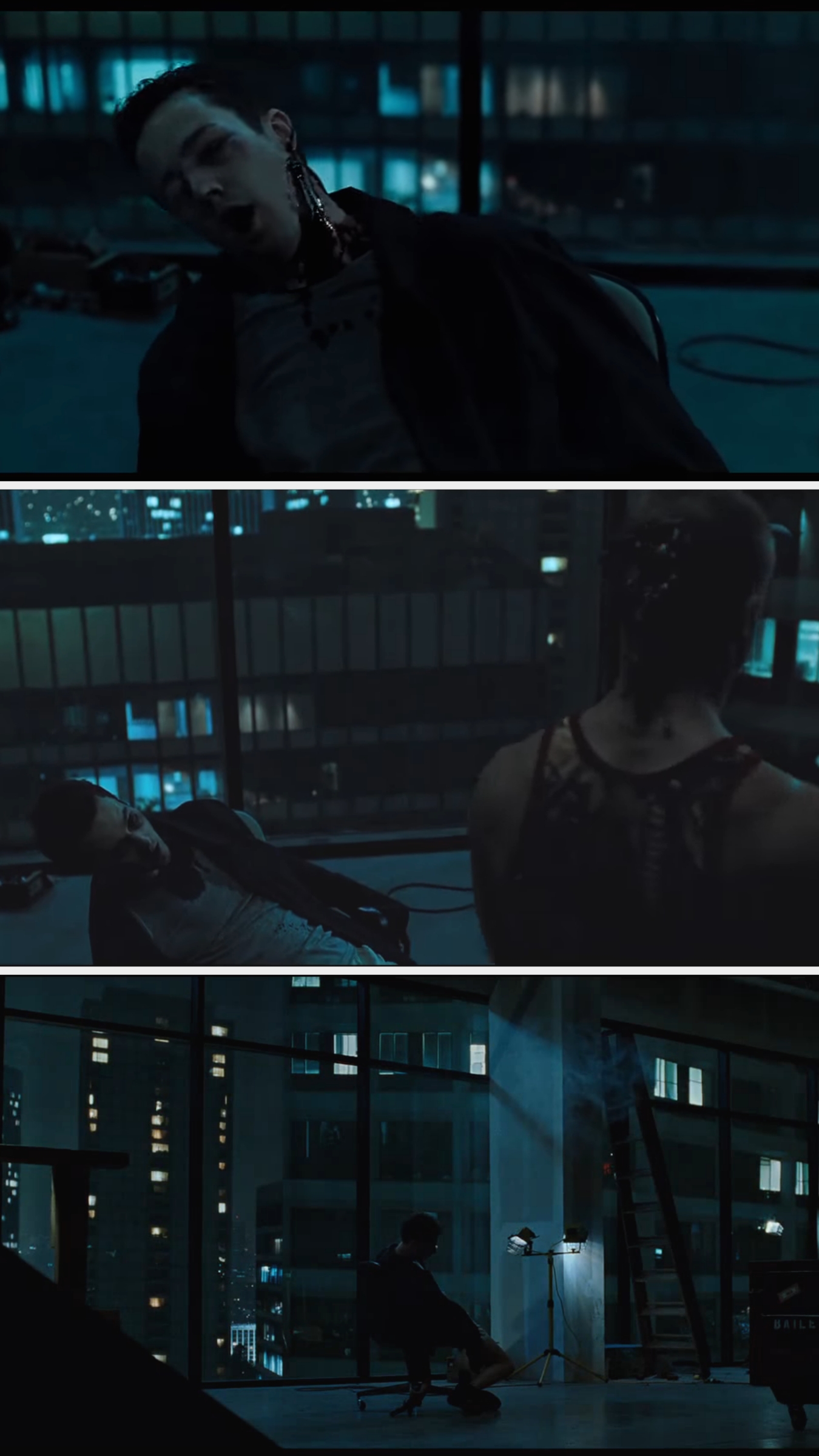 A person is tied to a chair in a dark office setting with large windows, appearing unconscious or exhausted. City lights are visible outside