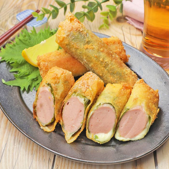 春巻きに似た料理が皿に盛られている。ソーセージとチーズが入っており、レモンスライスと葉が添えられている。