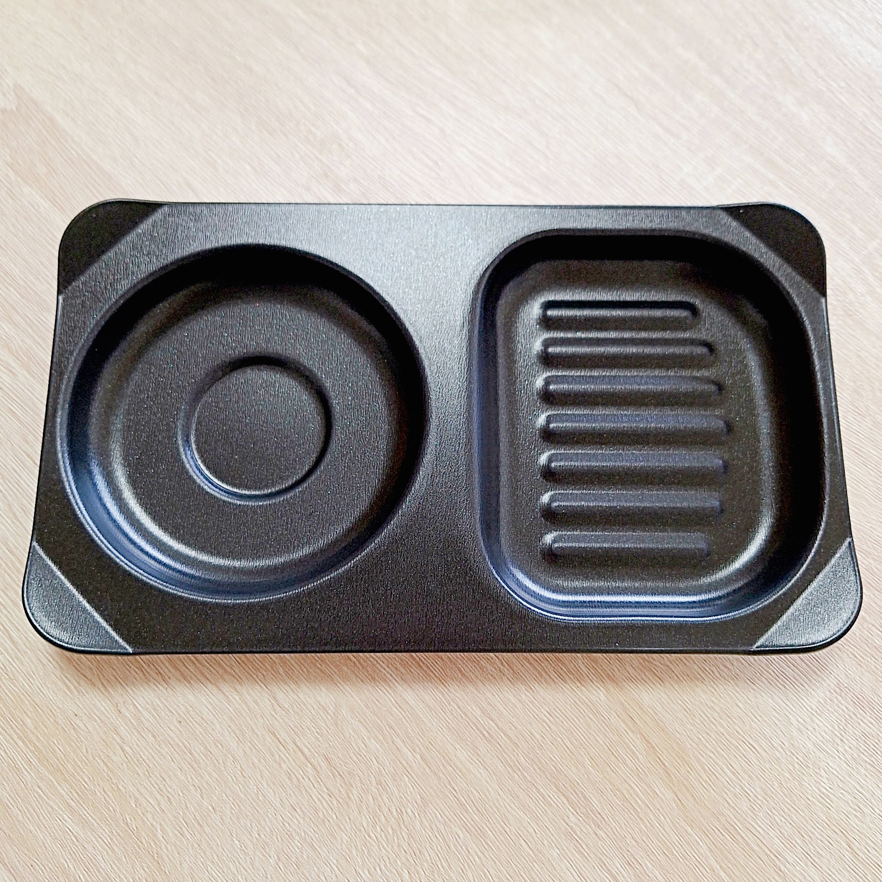 黒いプラスチック製の2つの区画がある弁当箱。