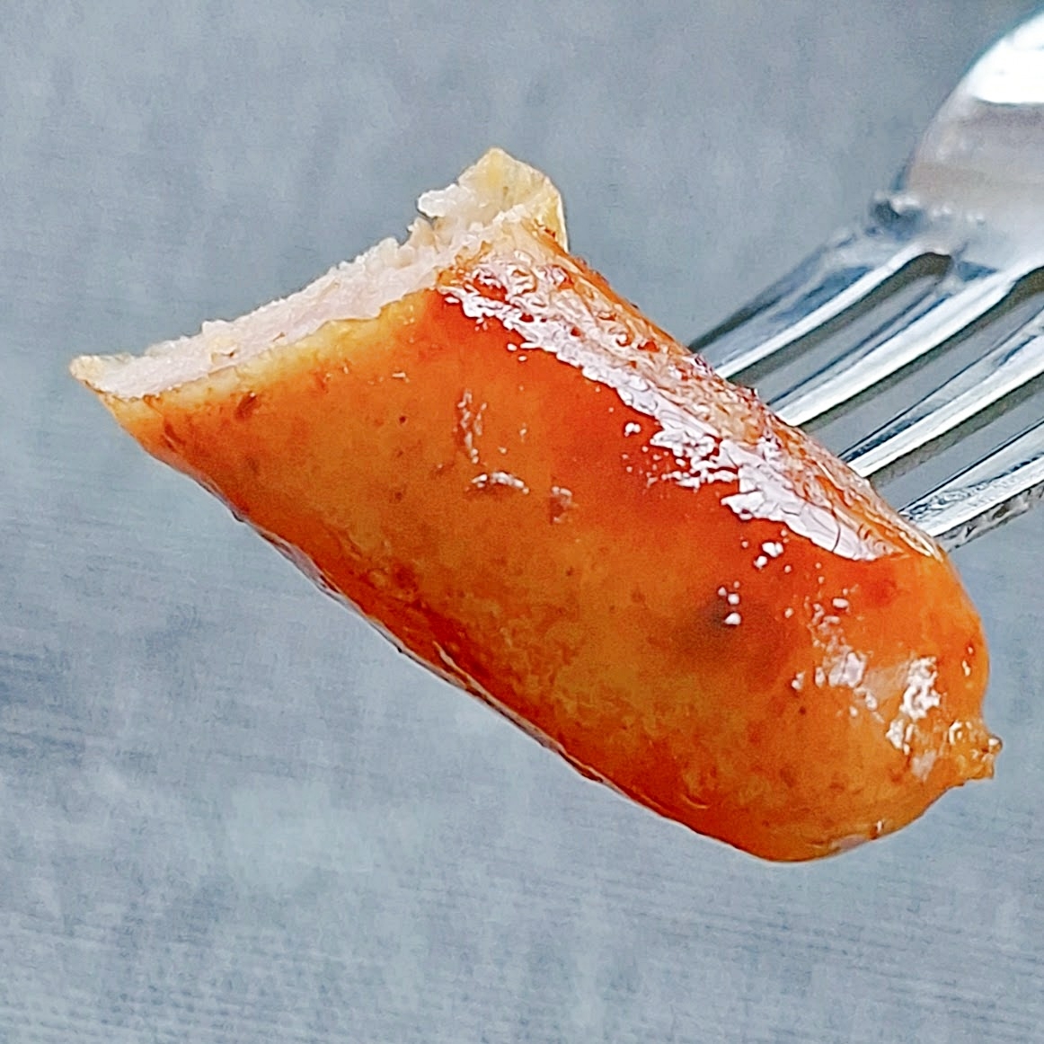 フォークで刺した一口大のソーセージの断面。ジューシーで食欲をそそる。