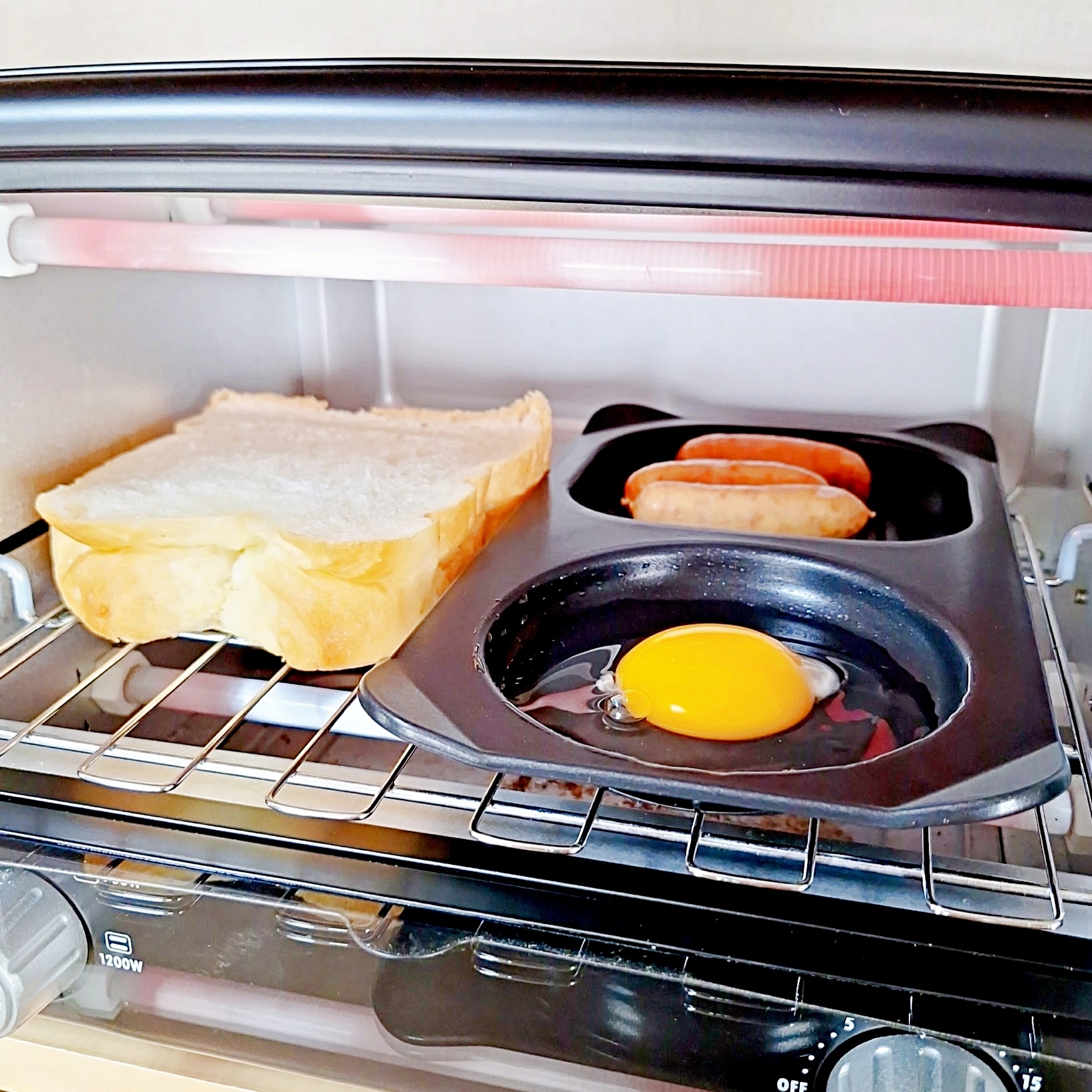トースター内で食パン、卵、ソーセージが調理されている様子。