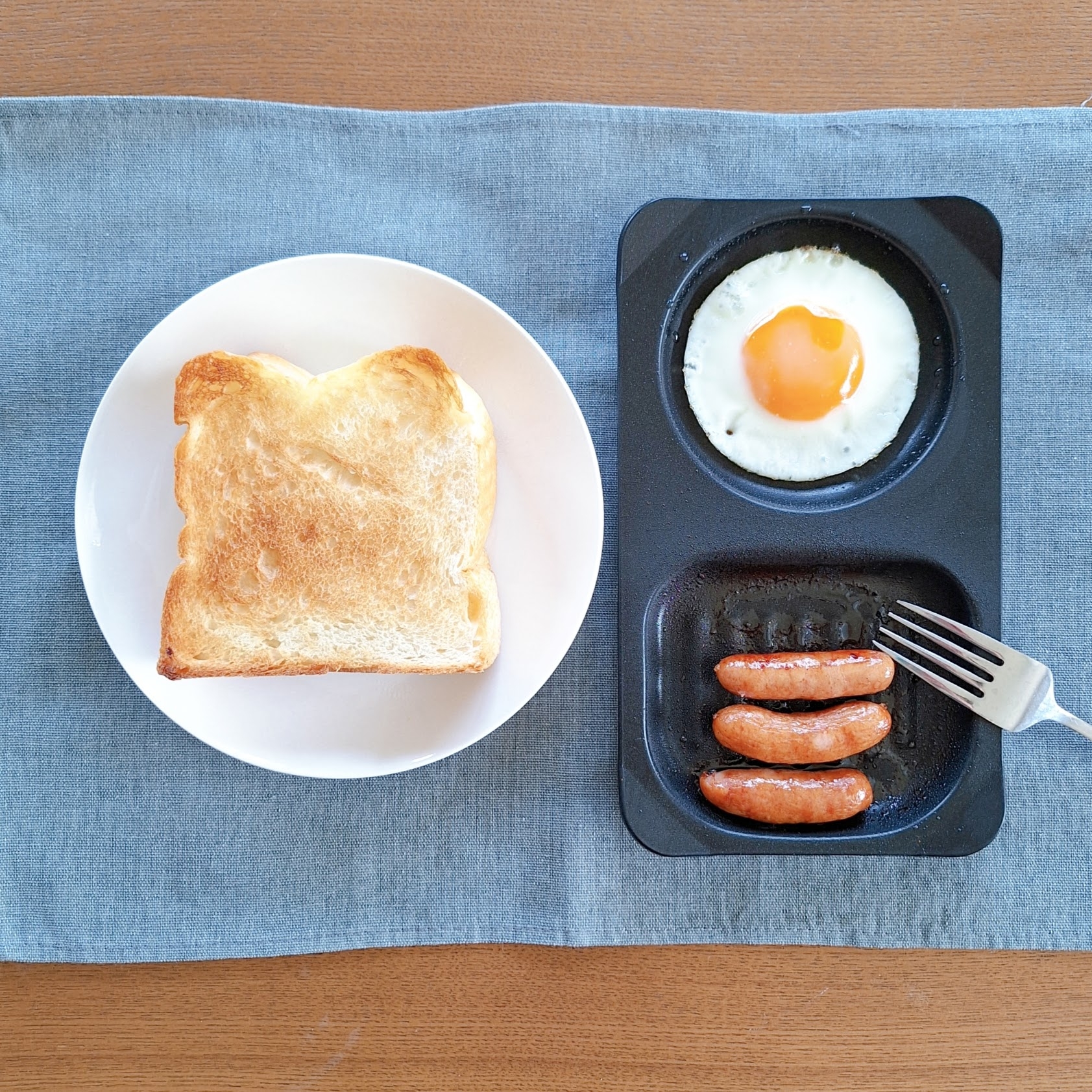 トーストと目玉焼き、ソーセージが乗った朝食プレート。