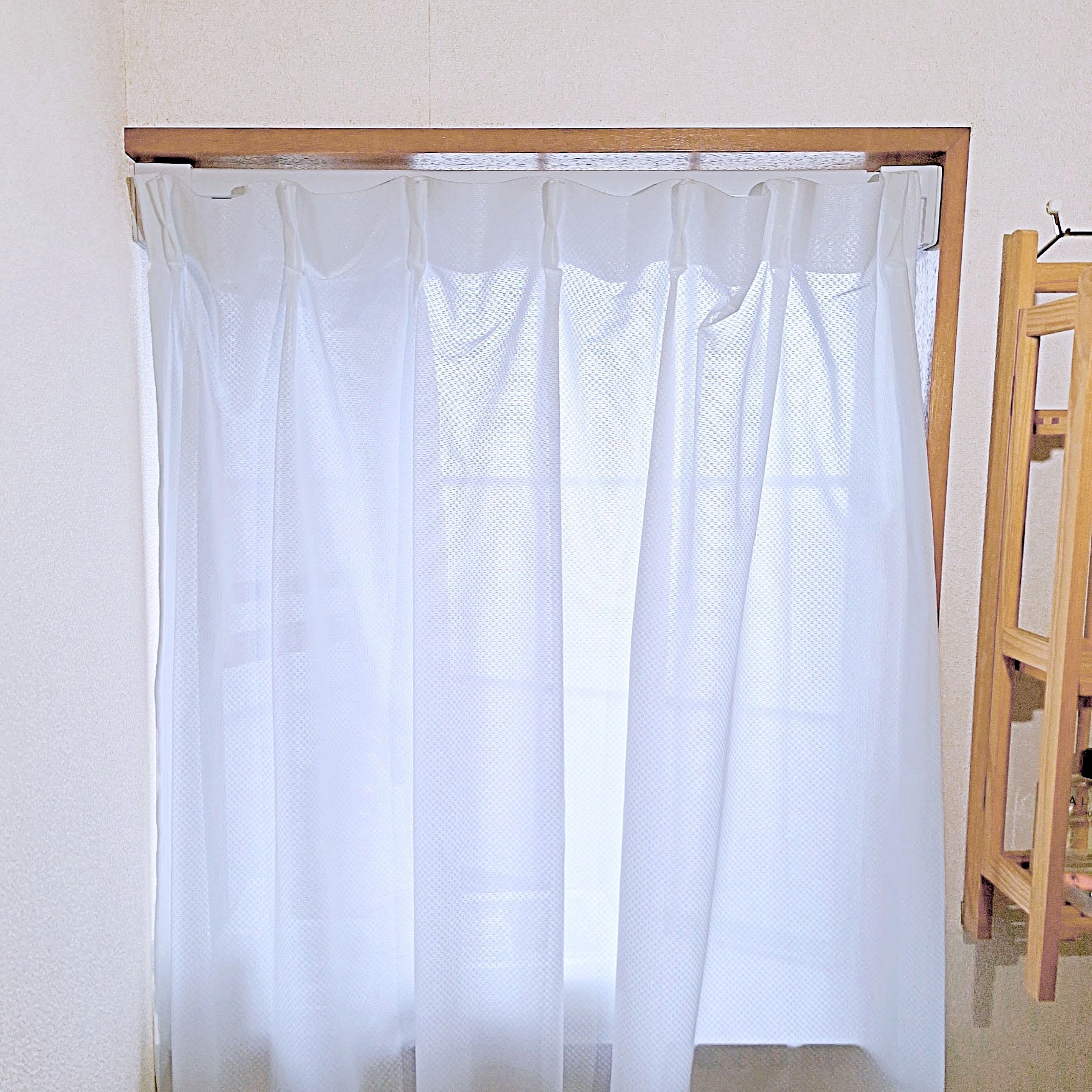 白いカーテンが窓を覆っている部屋の一部。シンプルでミニマルなインテリア。