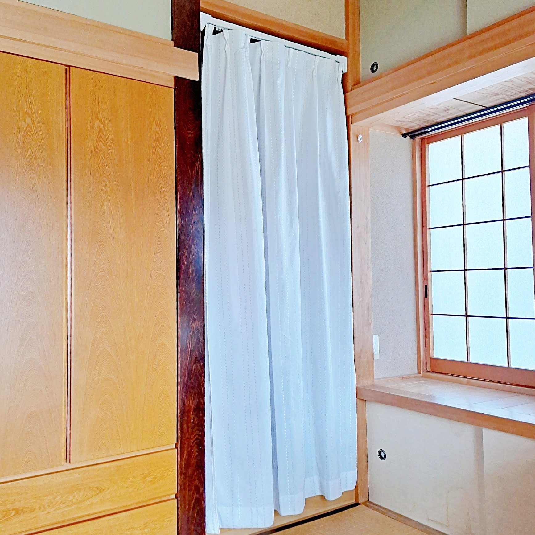 和室の一部、白いカーテンが窓を覆い、引き戸と木製の内装が見えるシンプルな室内。