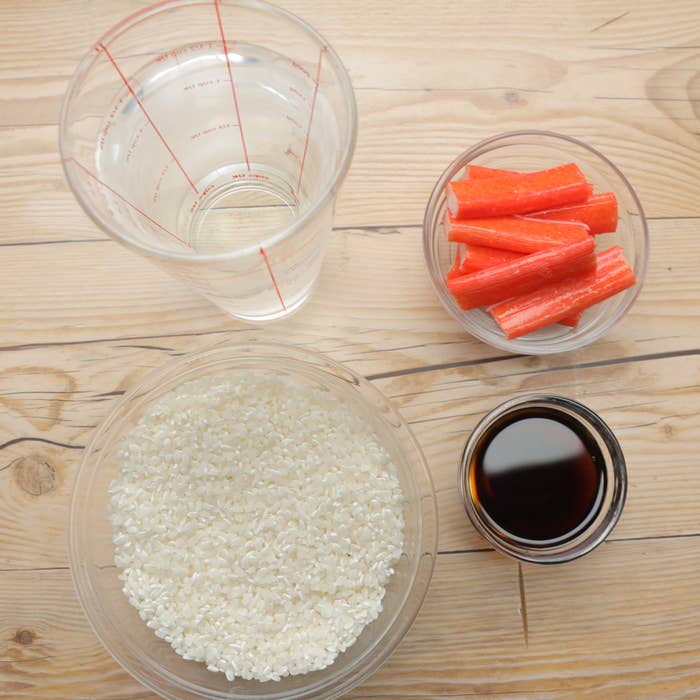 計量カップに水、カニカマ、白米が並ぶ調理用具のセット。