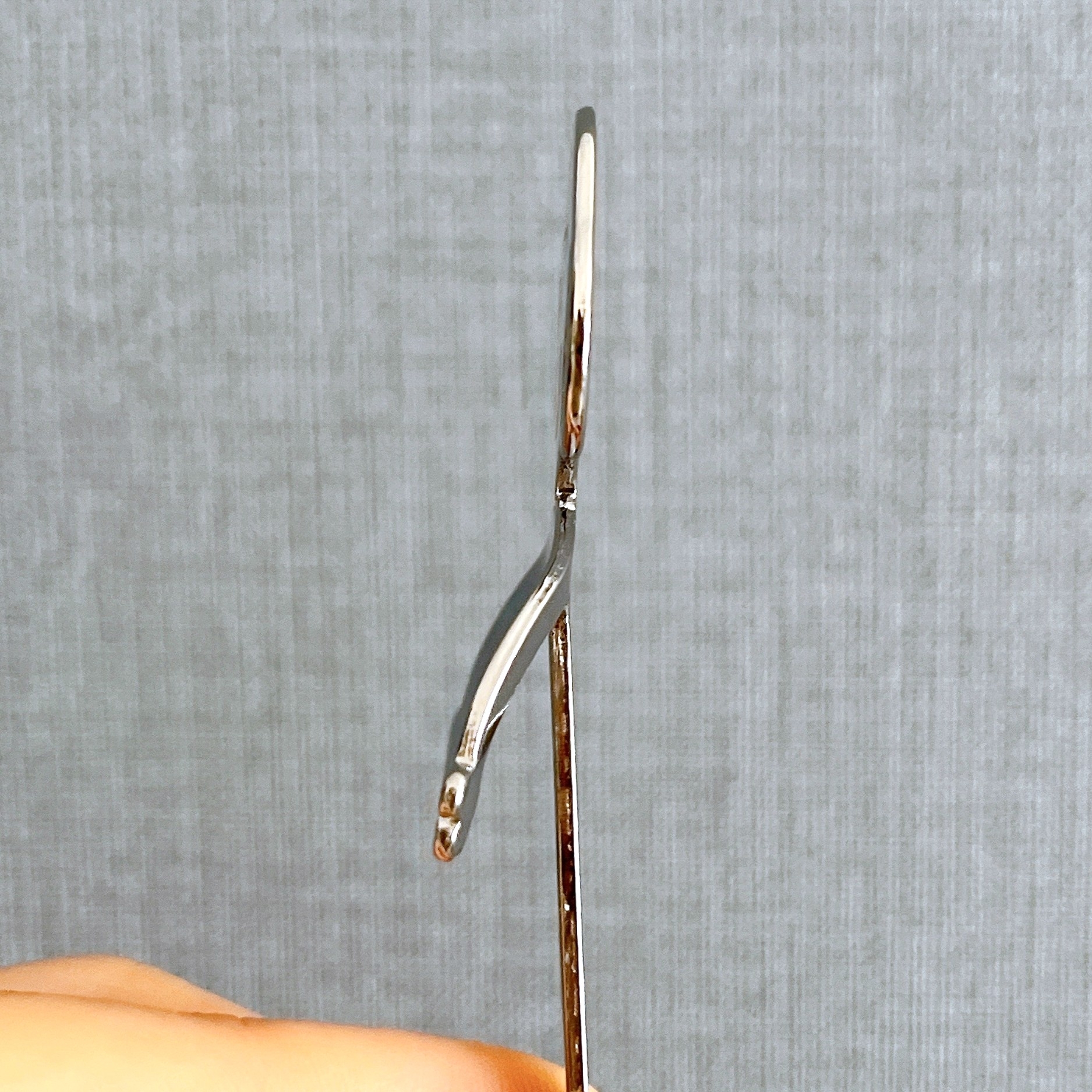 手に持たれた曲がった金属製のスプーンの横からのクローズアップ。