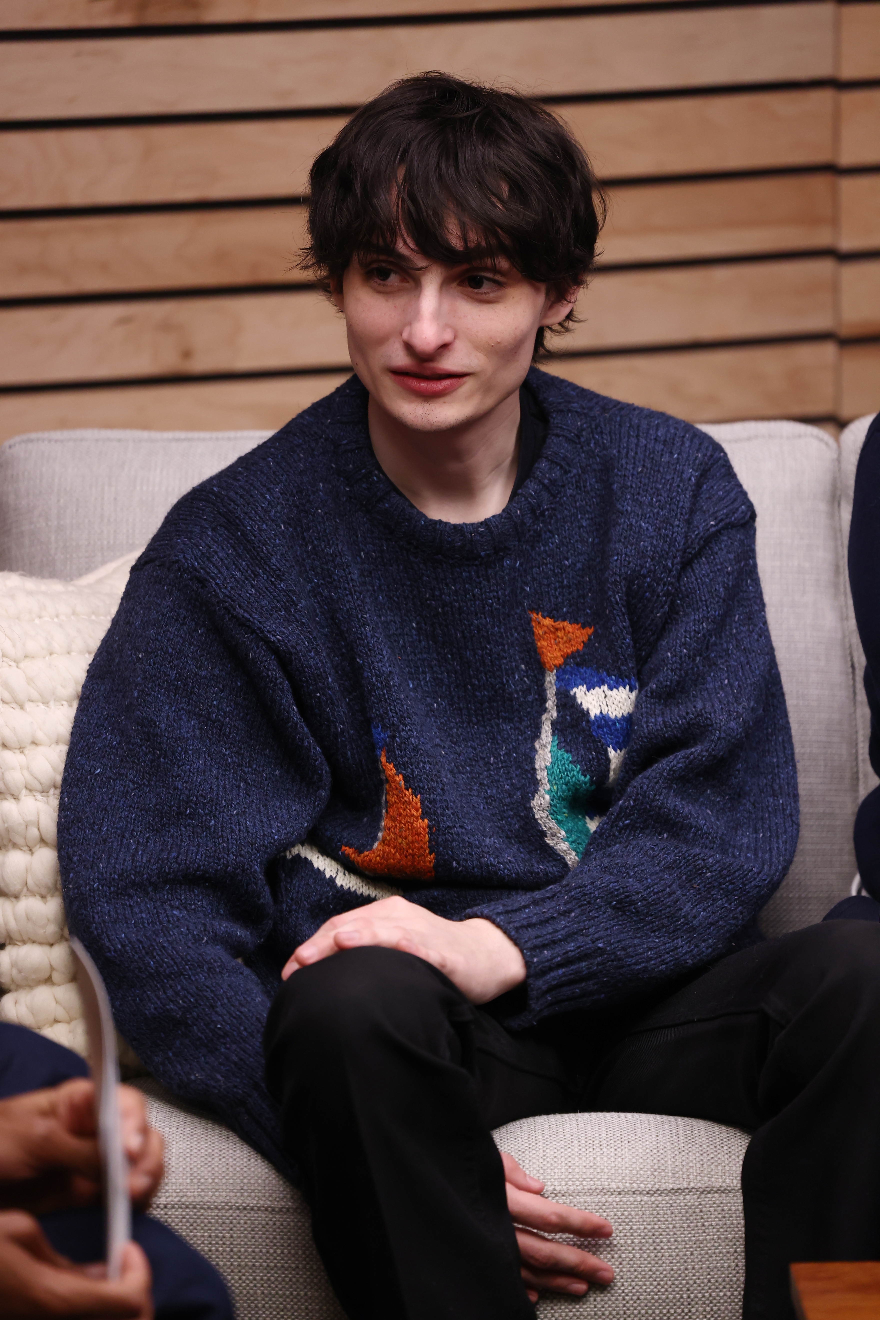 Finn Wolfhard sitting on a couch in a casual setting