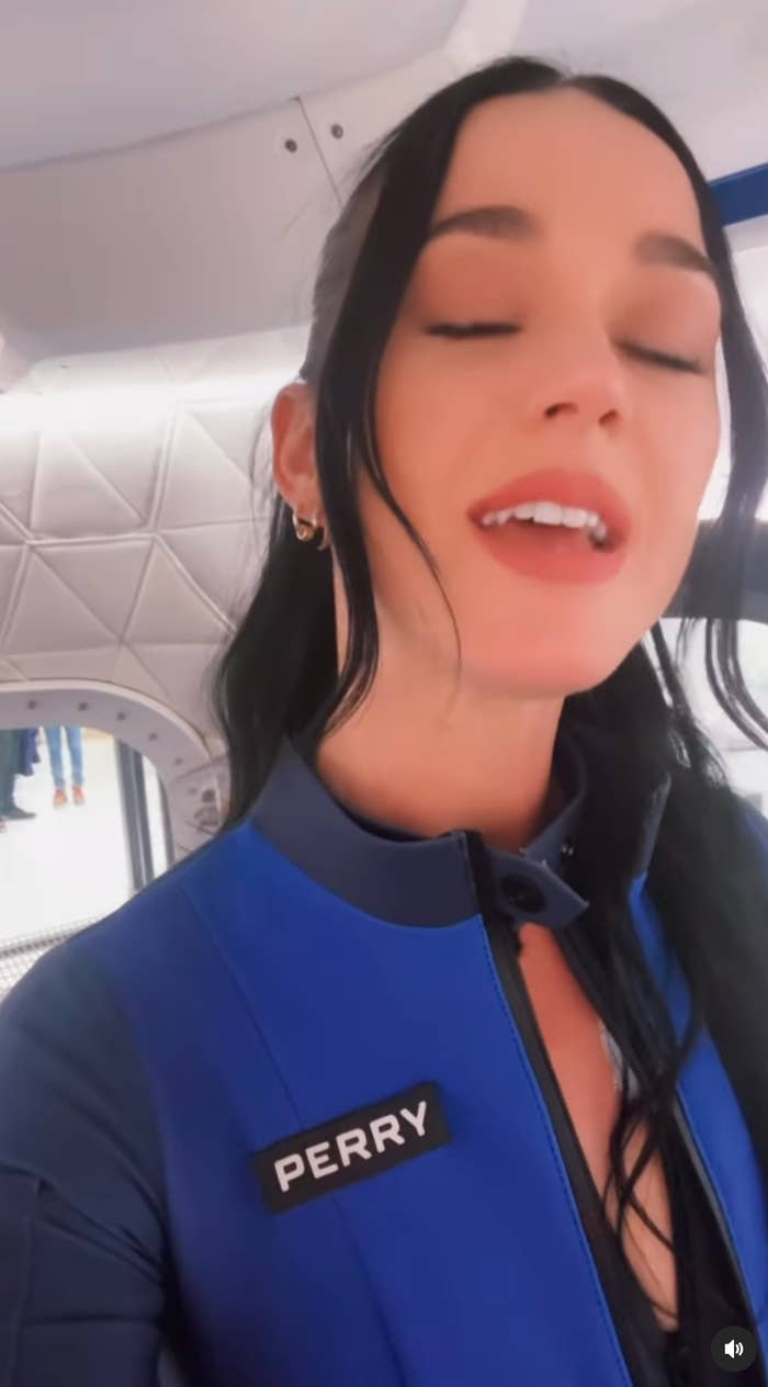 Person in a space-themed interior wearing a blue outfit with a name tag reading 