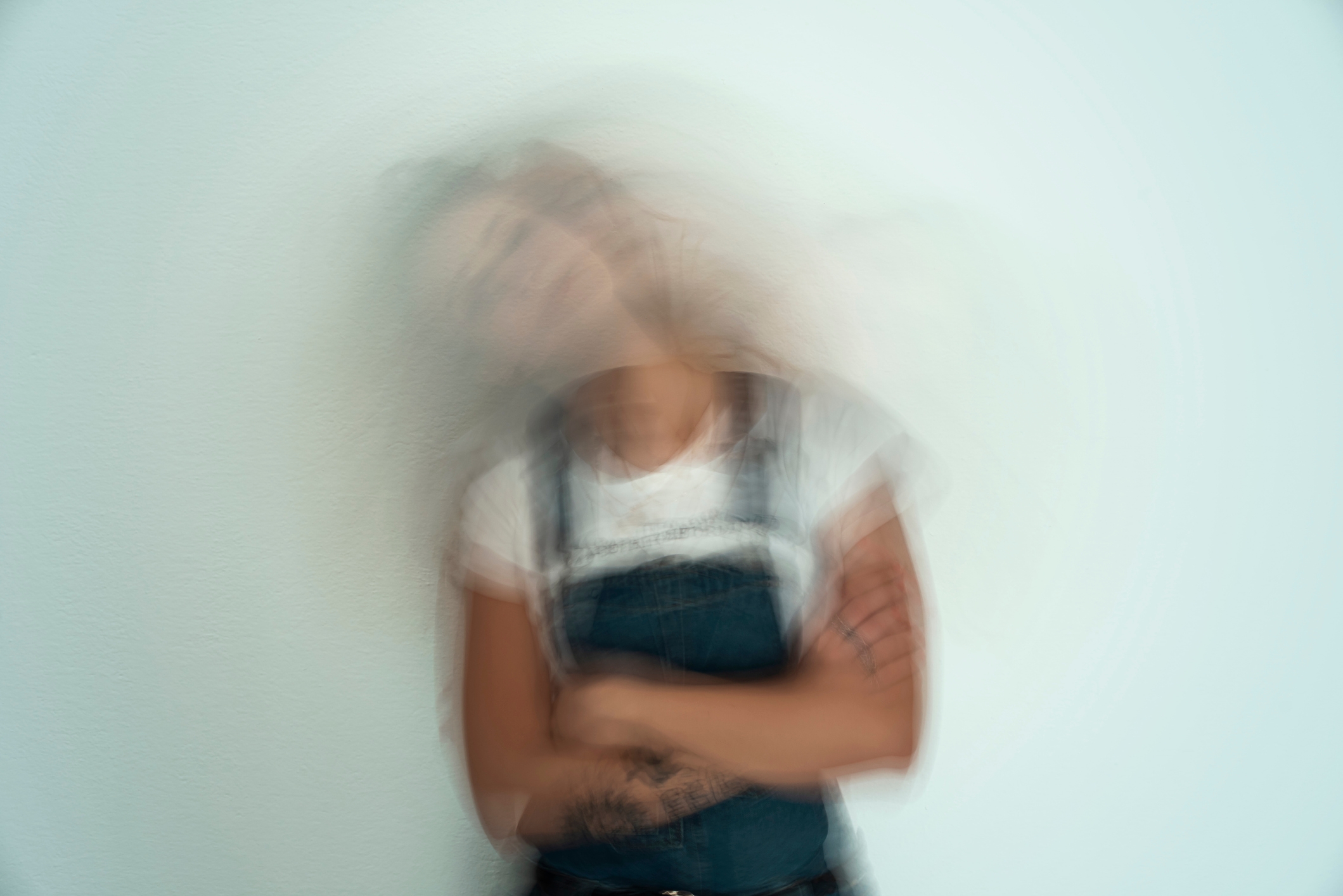 Uklart bilde av en person i kjeledress med krysset armer, noe som skaper en følelse av bevegelse eller forvirring