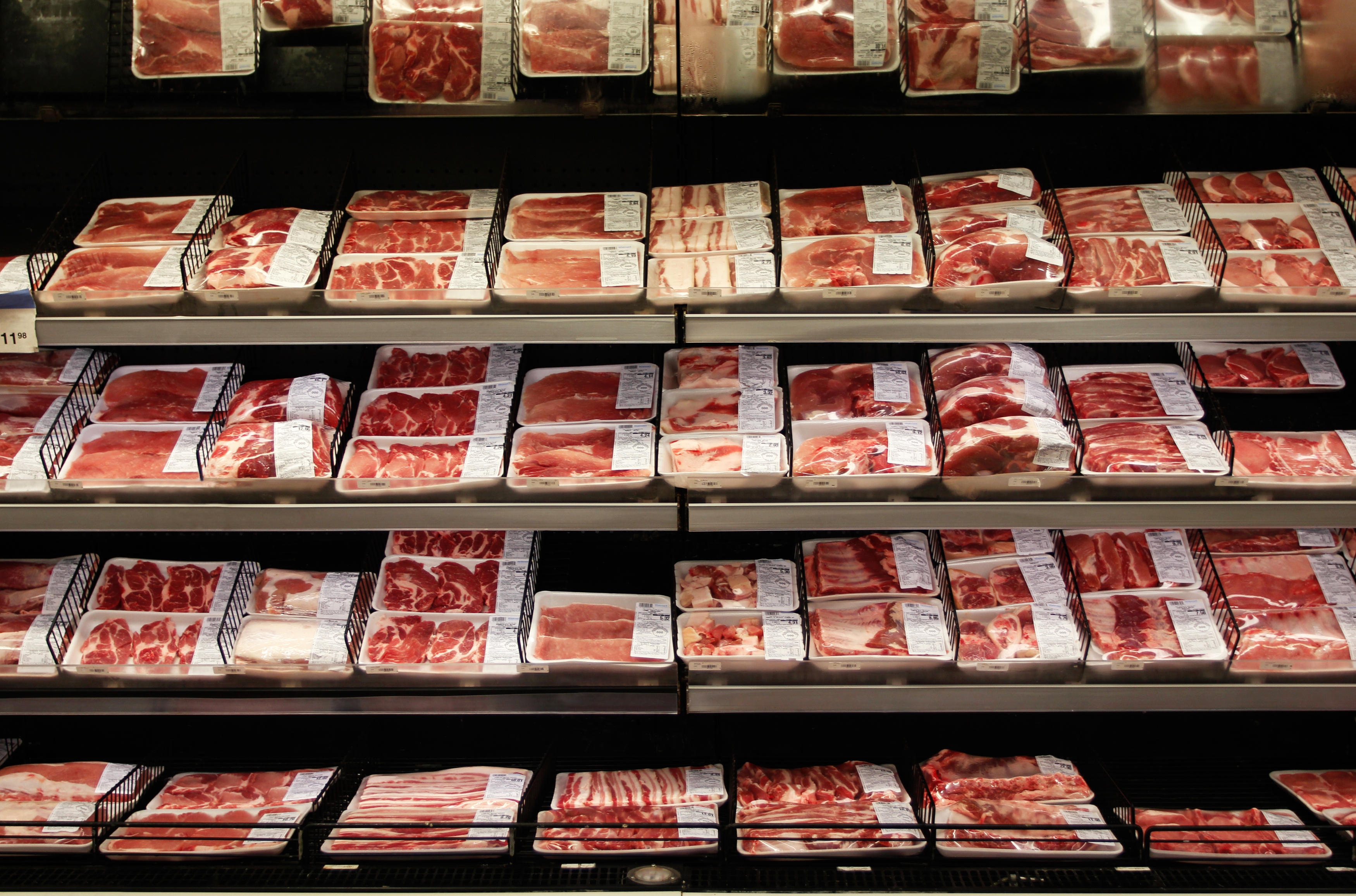 Various packaged meat cuts on display in a supermarket's refrigerated section