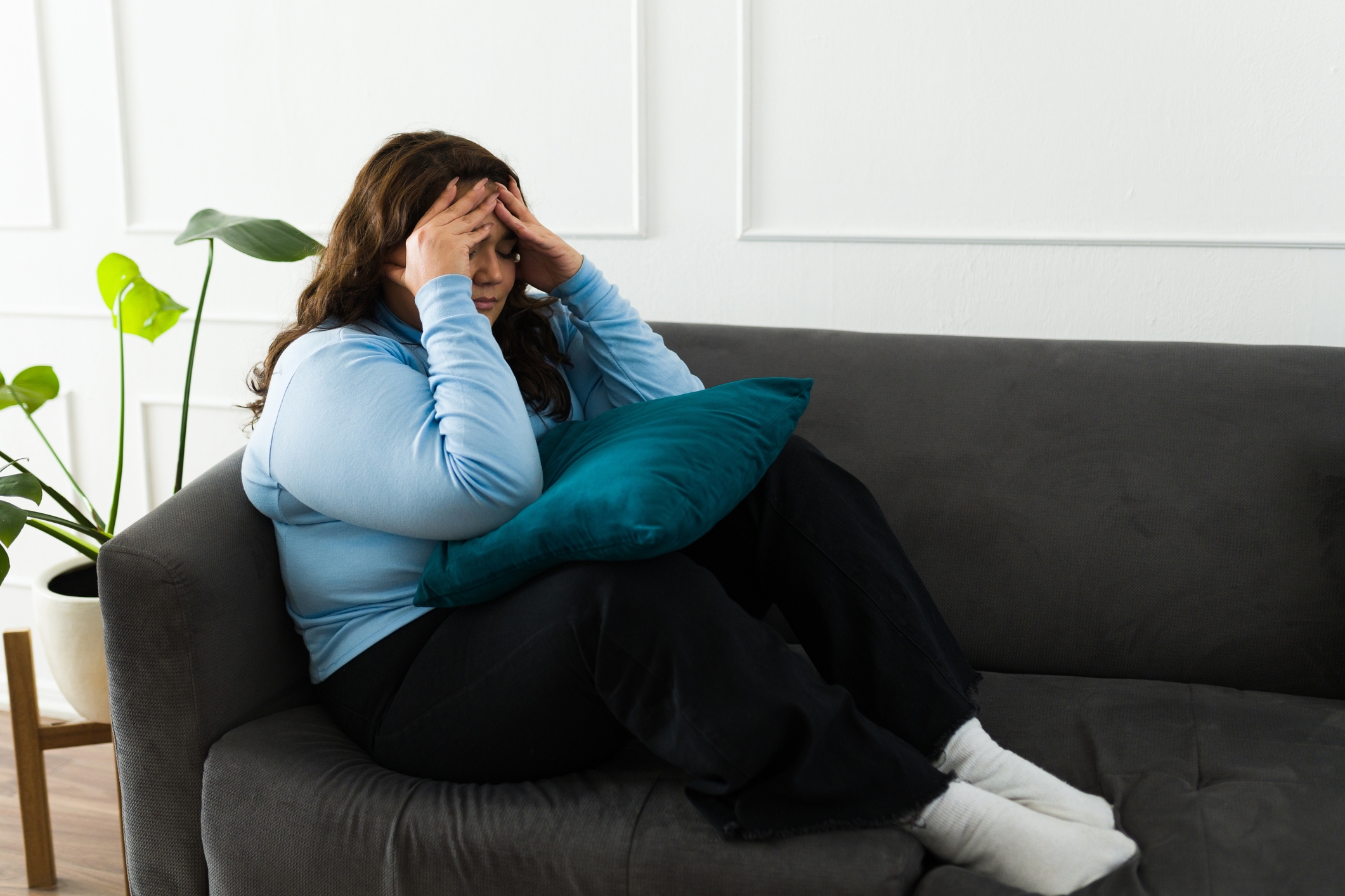Person på en sofa som holder en pute, ser stresset ut med hodet på hodet, i et fredelig boareal