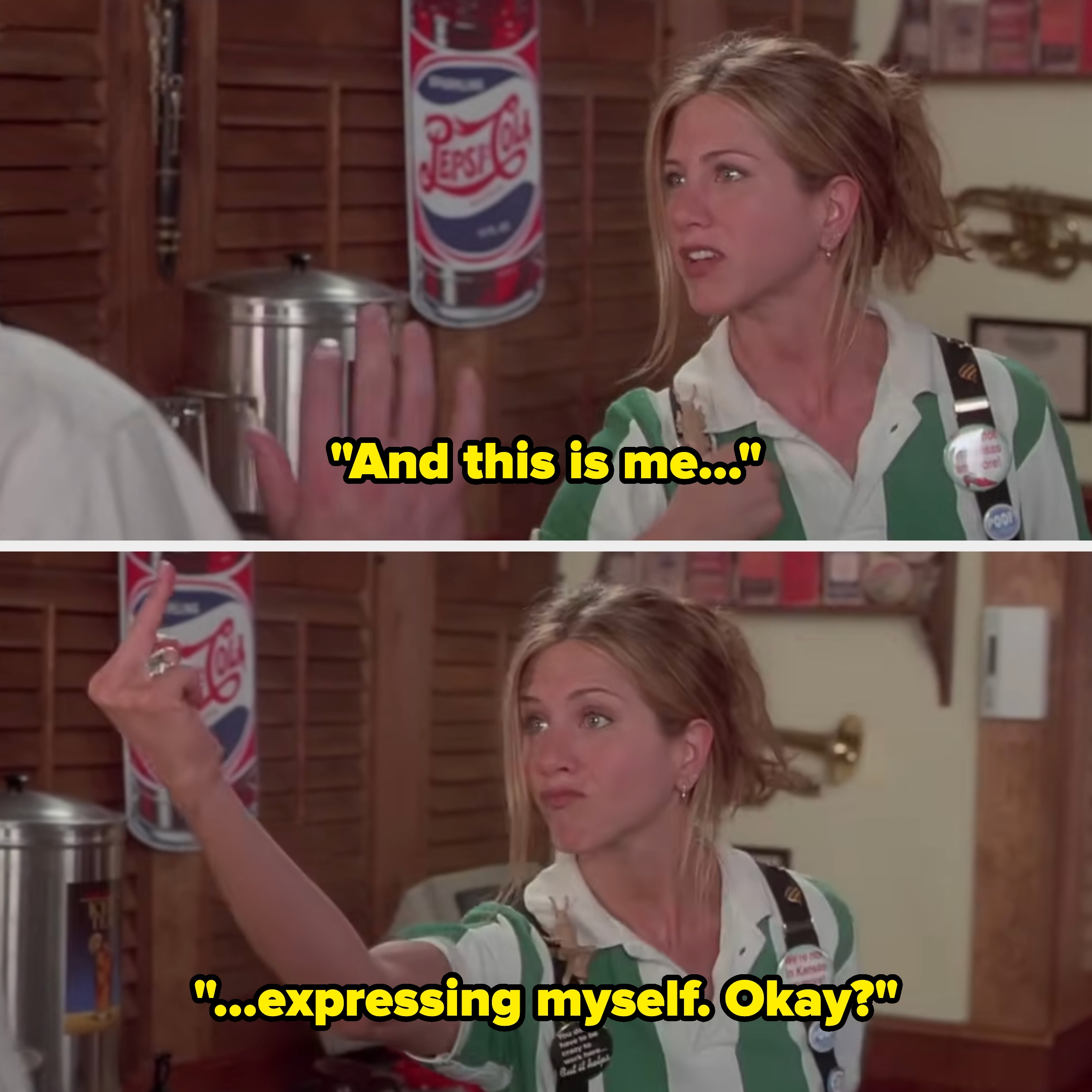 Person in a striped shirt, wearing flair buttons, gesturing with their hands in a humorous scene from a film set in a workplace