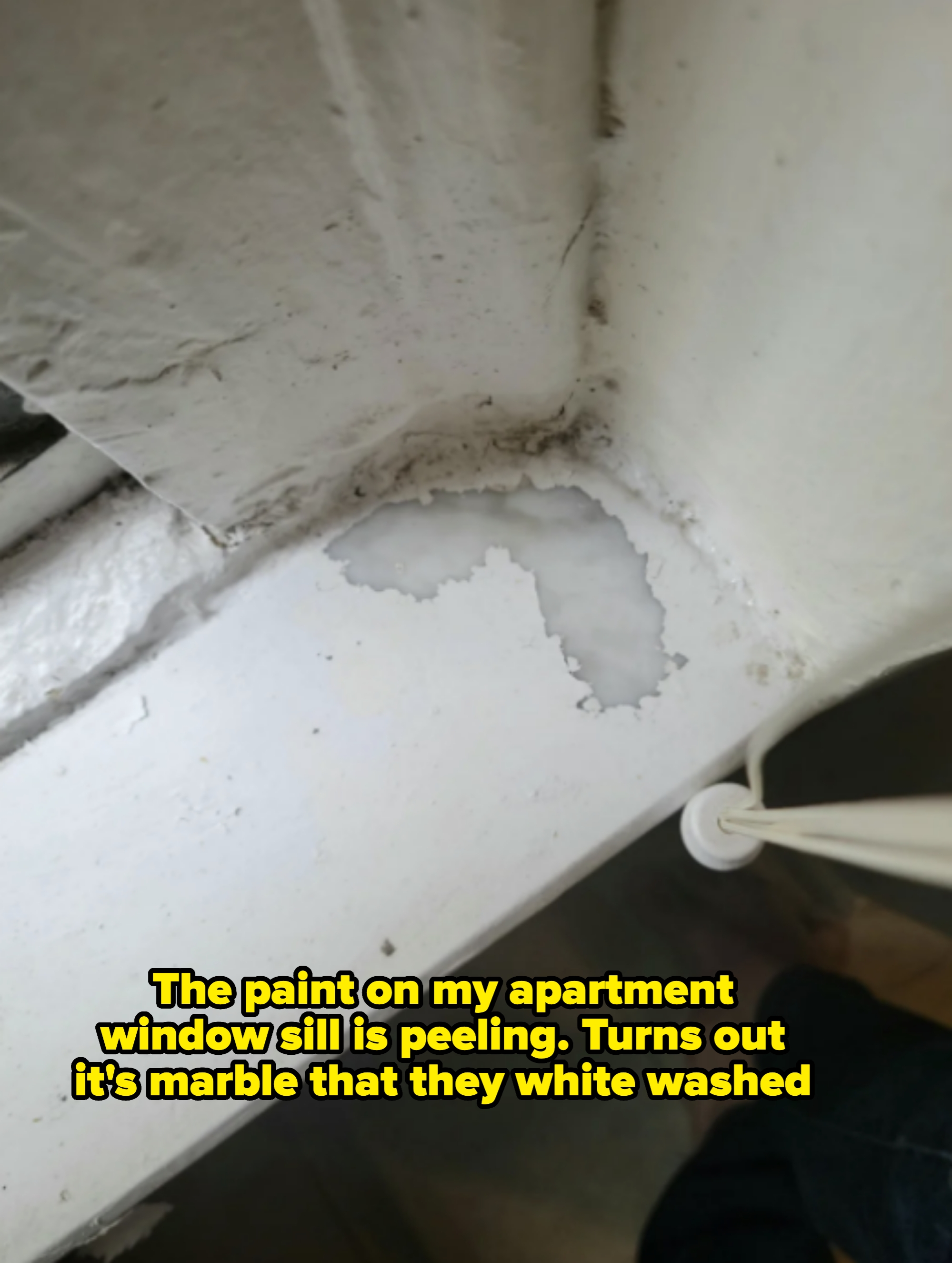 Peeling paint on marble apartment windowsill with note about landlord having painted it